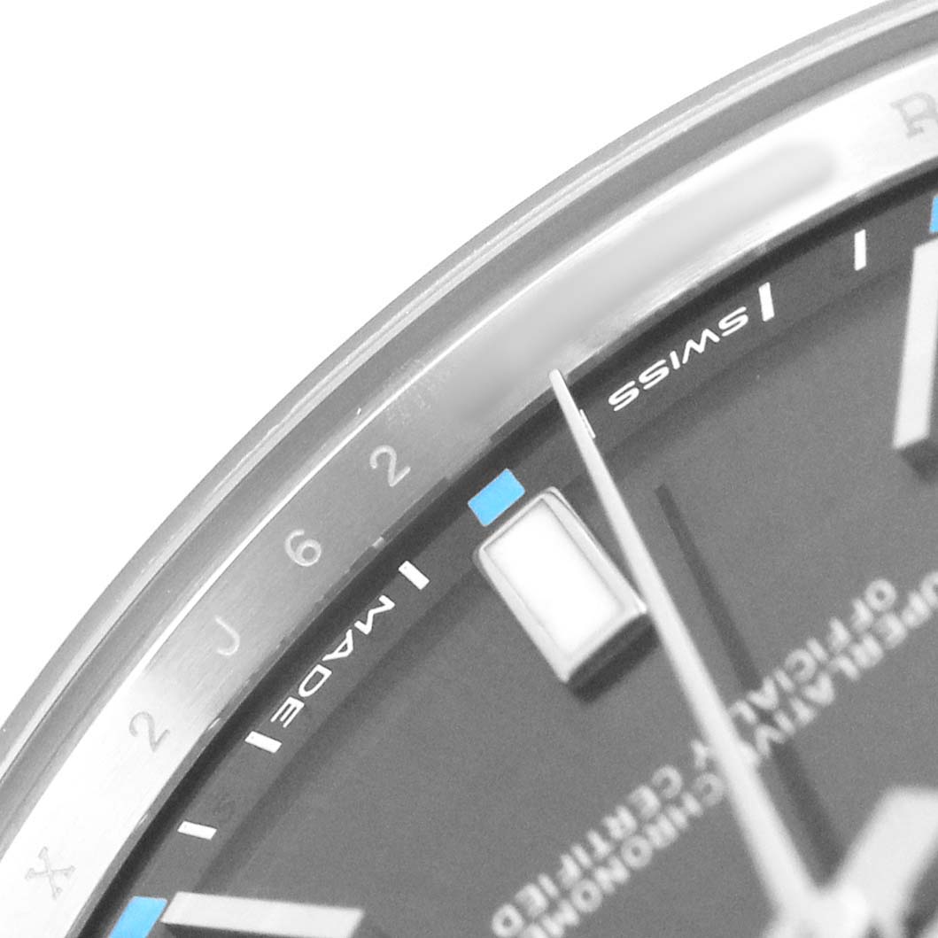 This image shows a close-up of a Rolex Oyster Perpetual 114300 Men's Stainless Steel Grey Dial watch's dial, with parts of the bezel, numerals, and markers visible.