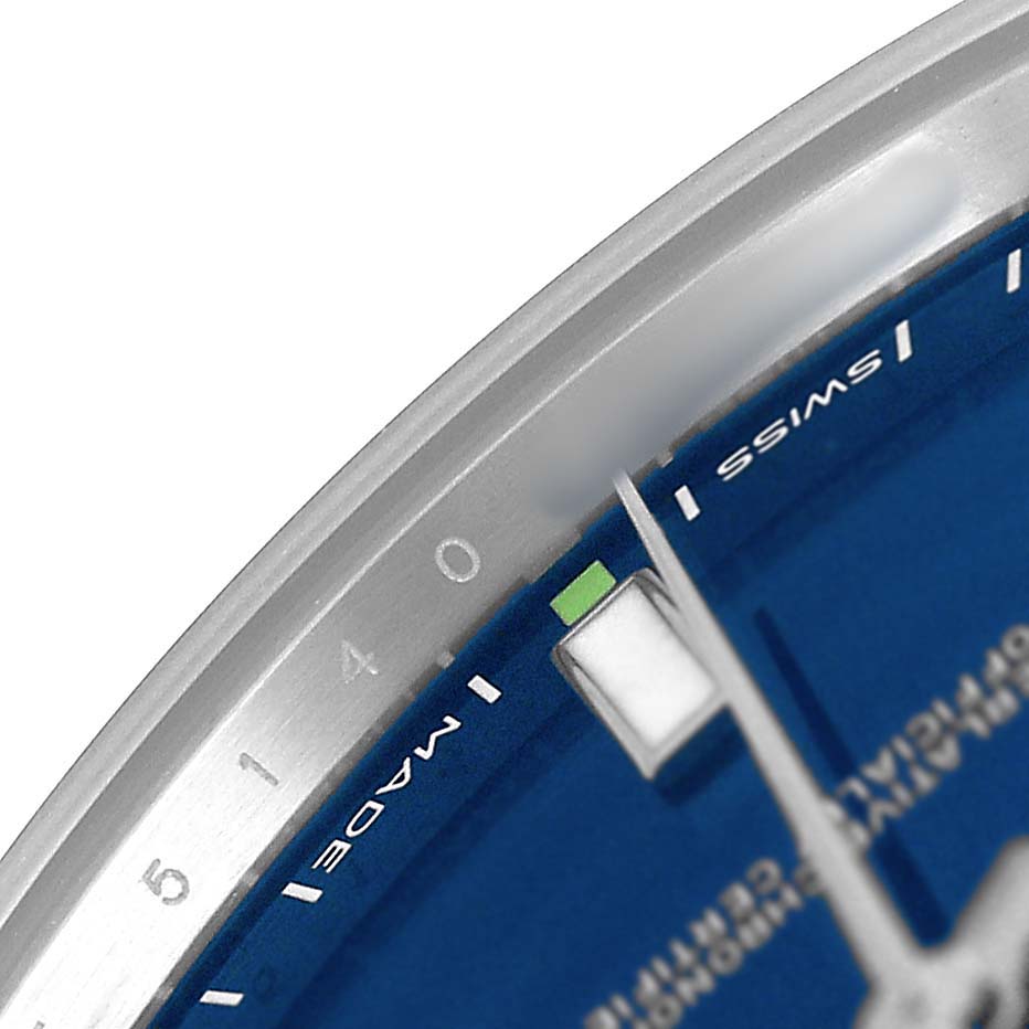 The image shows a close-up of the dial edge and hands of a Rolex Oyster Perpetual 114300 Men's Stainless Steel Blue Dial watch.