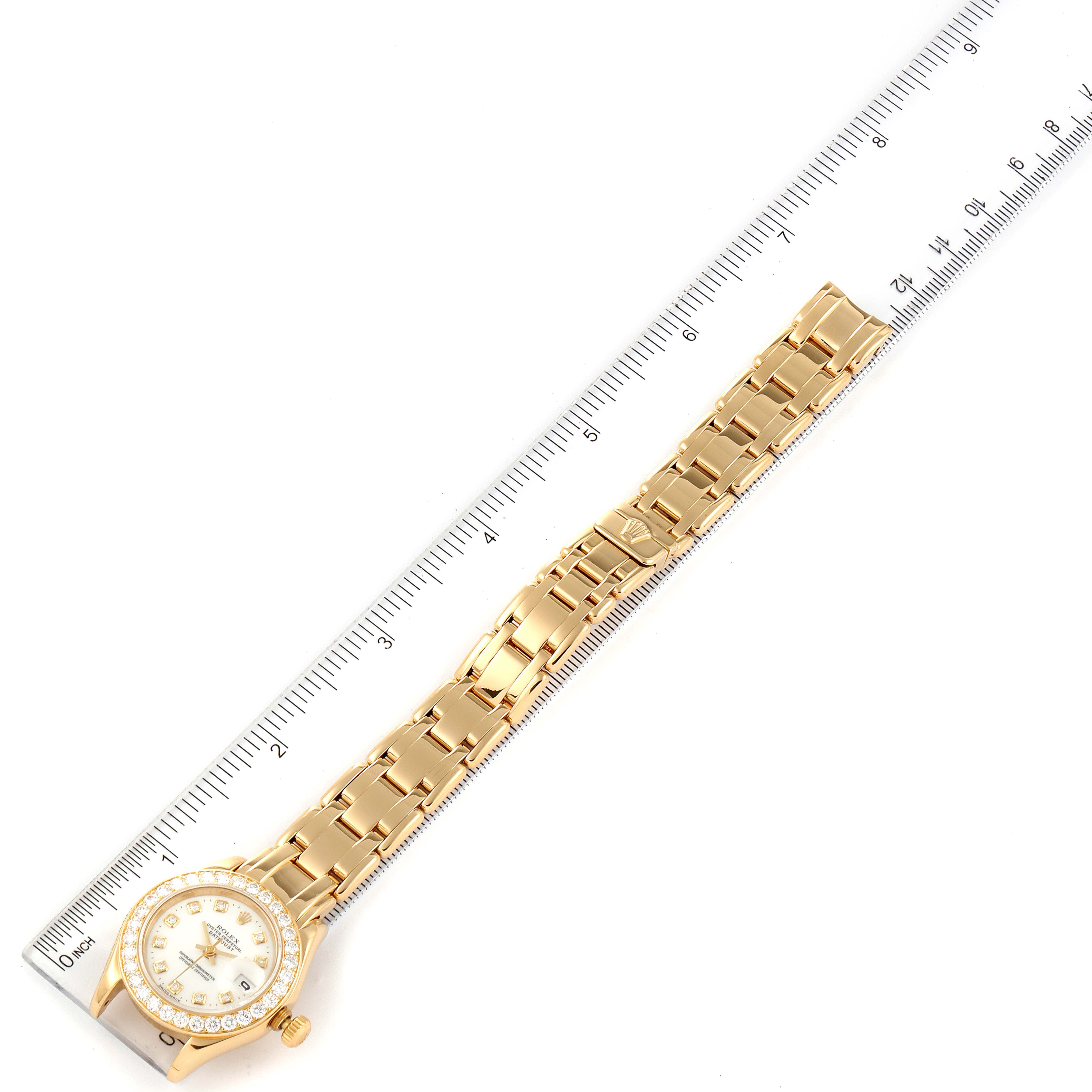 The image shows a Rolex Pearlmaster 69298 Women's Yellow Gold Mother of Pearl Dial 69298 Women's Yellow Gold Mother of Pearl Dial watch laid flat next to a ruler, displaying the face and entire bracelet from an top-down angle.