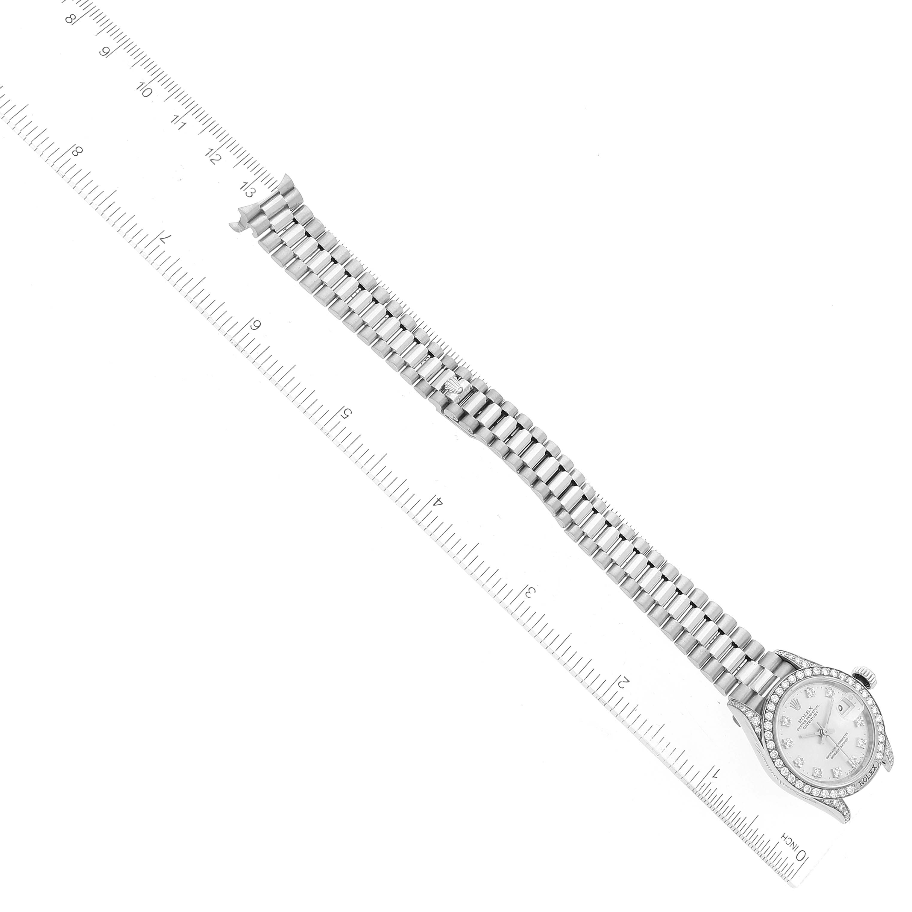 The image shows a top-down view of a Rolex President 69159 Women's White Gold Silver Dial 69159 Women's White Gold Silver Dial model watch, displaying the face and bracelet, with a ruler for scale.