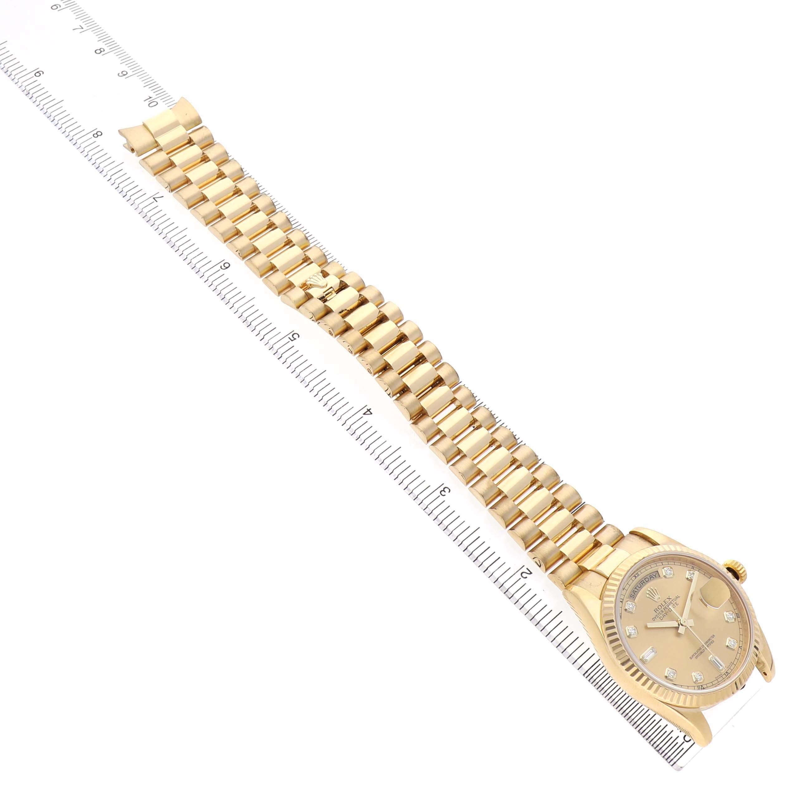 The Rolex President 118238 Men's Yellow Gold Champagne Dial model watch is shown at an angle highlighting the watch face, bracelet, and clasp alongside a ruler.