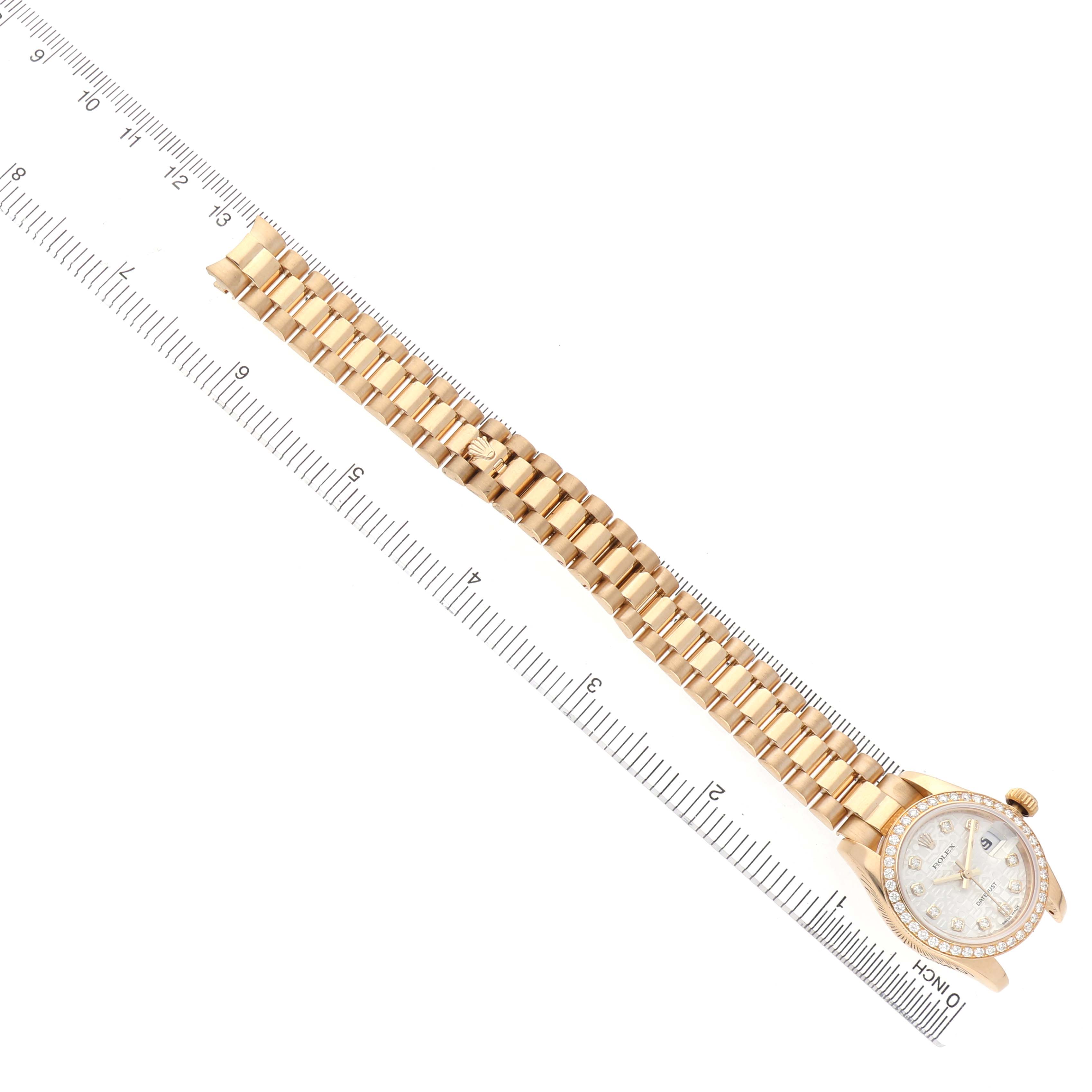 The Rolex President 179138 Women's Yellow Gold Silver Dial watch is shown at a top angle, highlighting its gold bracelet and bezel alongside a ruler for scale.