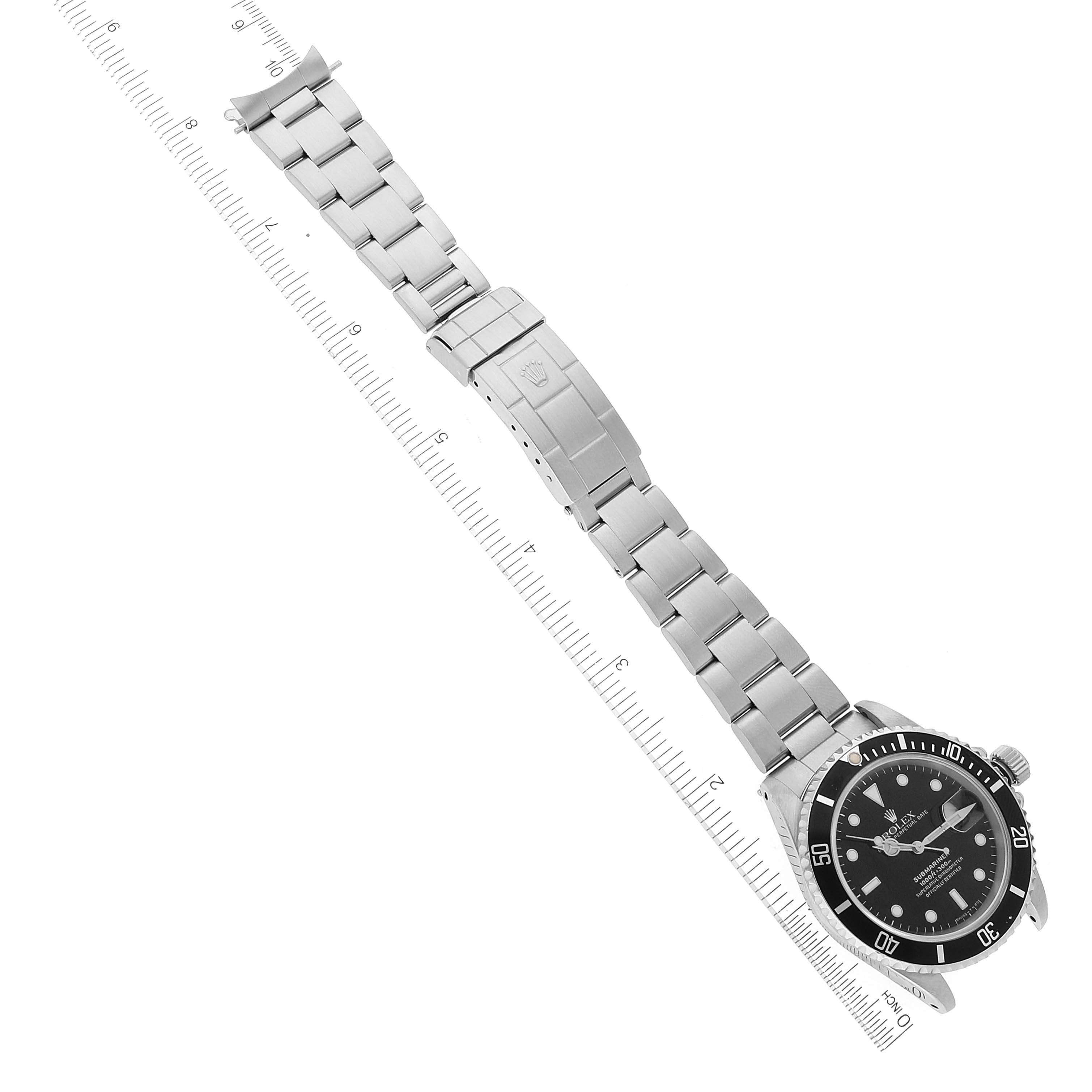 The image shows a full stainless steel Rolex Submariner 16610 Men
s Stainless Steel Black Dial 16610 Men
s Stainless Steel Black Dial watch lying flat with the case, dial, and bracelet fully visible alongside a ruler for scale.