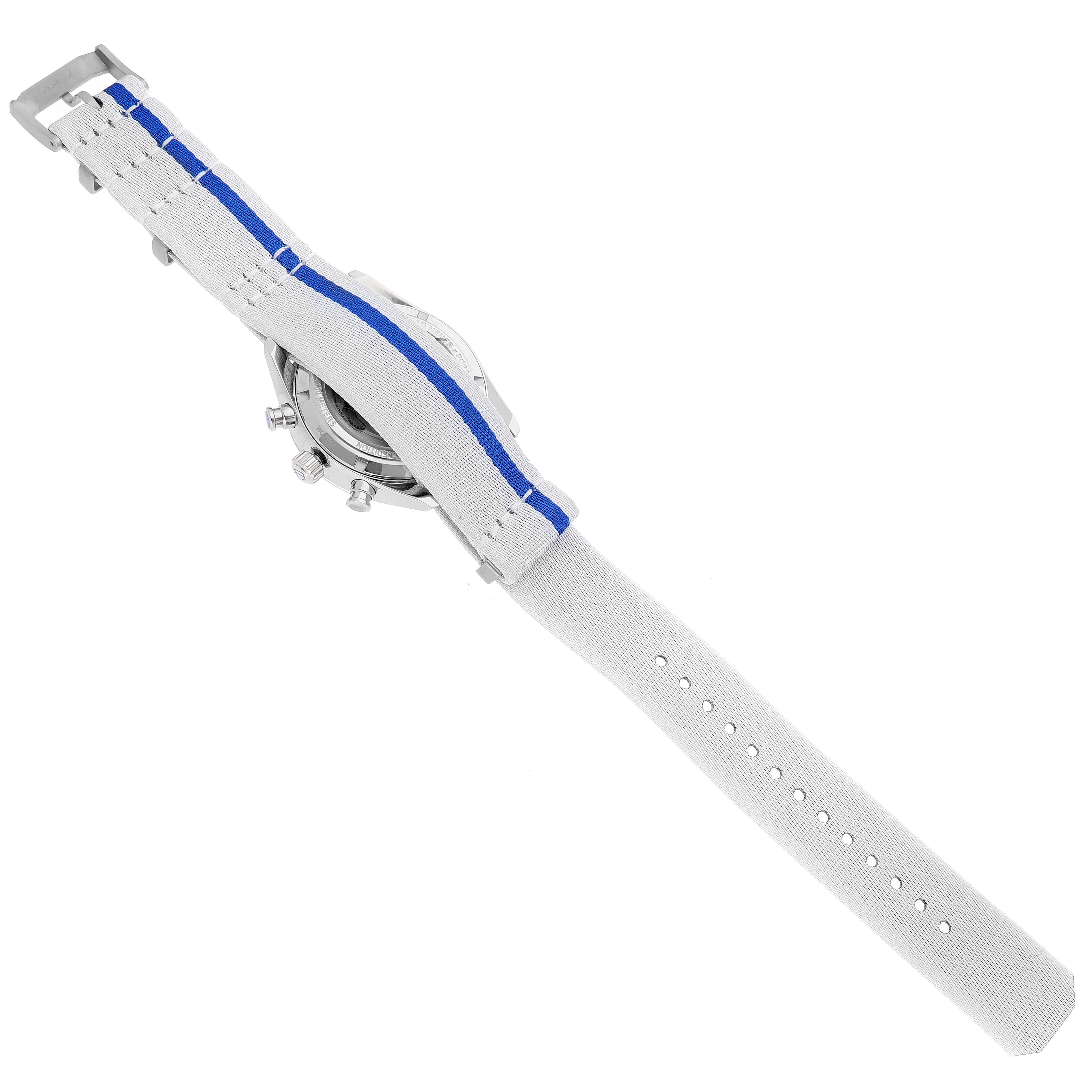 This image shows the back view of a Tag Heuer Carrera watch with a light grey strap featuring a blue stripe.