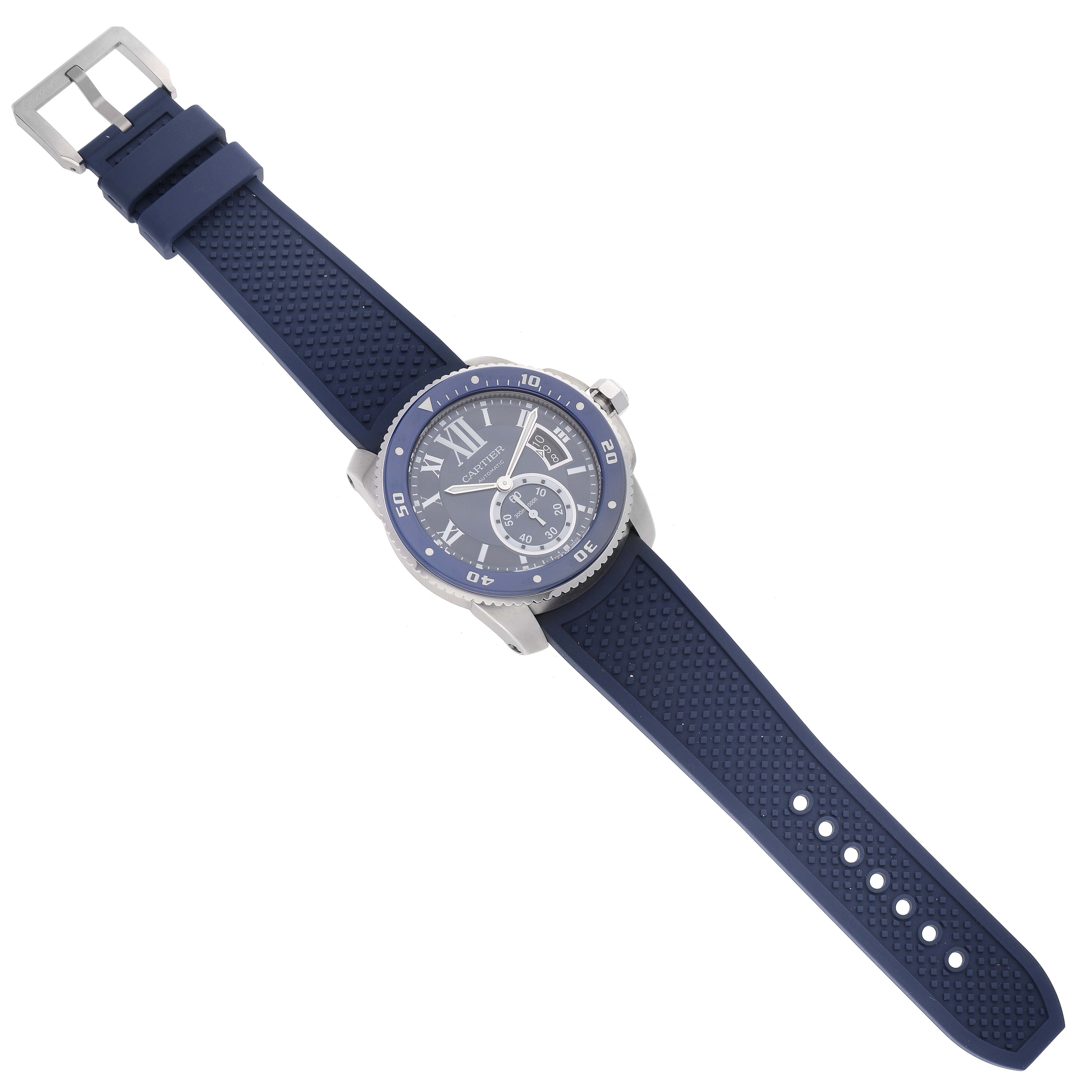 The image shows a Calibre de Cartier watch by Cartier, viewed from above, displaying the face, bezel, crown, and blue strap.