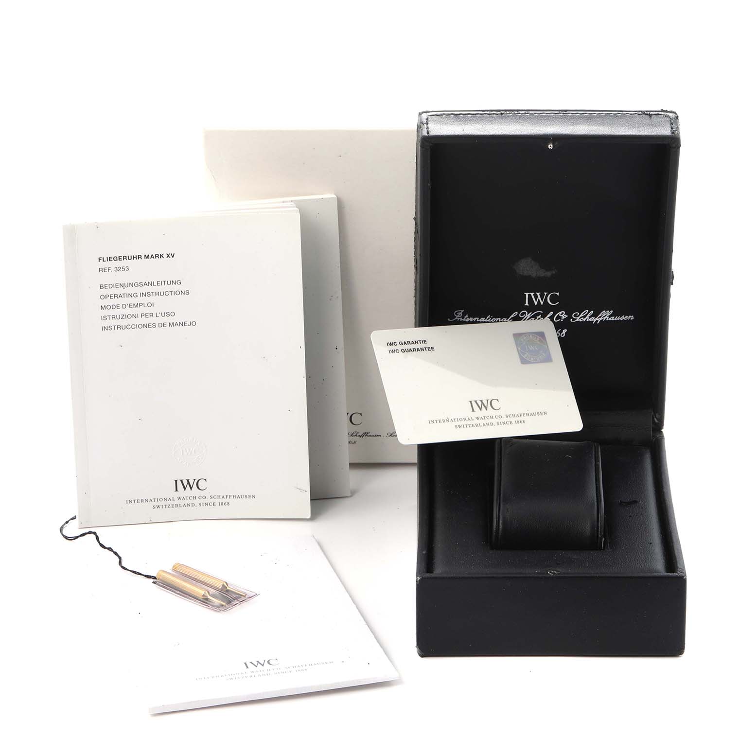 The image shows an IWC Pilot IW325505 Men
s Stainless Steel Silver Dial IW325505 Men
s Stainless Steel Silver Dial model watch box, manuals, guarantee card, and extra strap parts from an overhead angle.