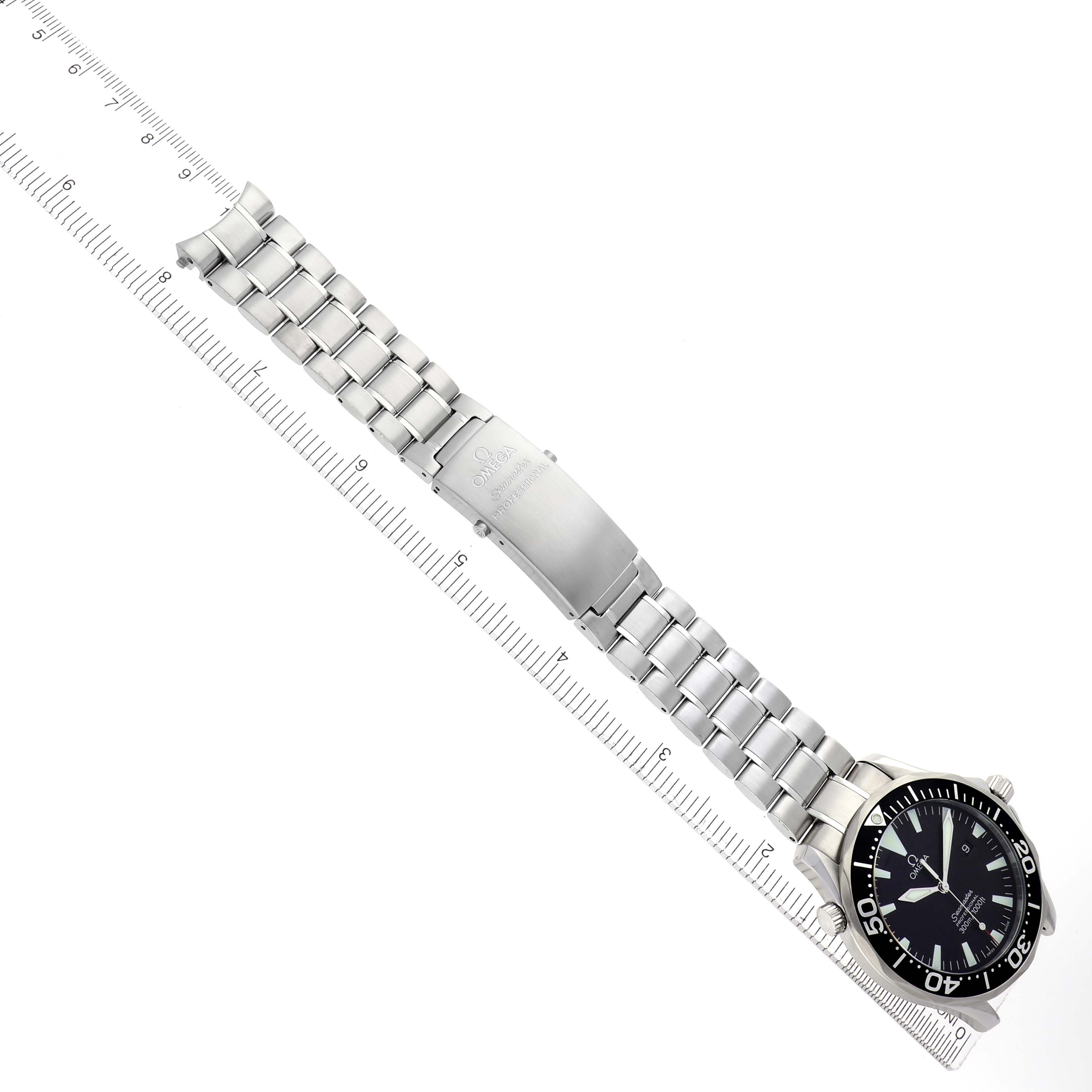 The Omega Seamaster 2264.50.00 Men
s Stainless Steel Black Dial 2264.50.00 Men
s Stainless Steel Black Dial watch is shown from a top view, displaying its bracelet, clasp, dial, and part of the bezel next to a ruler.