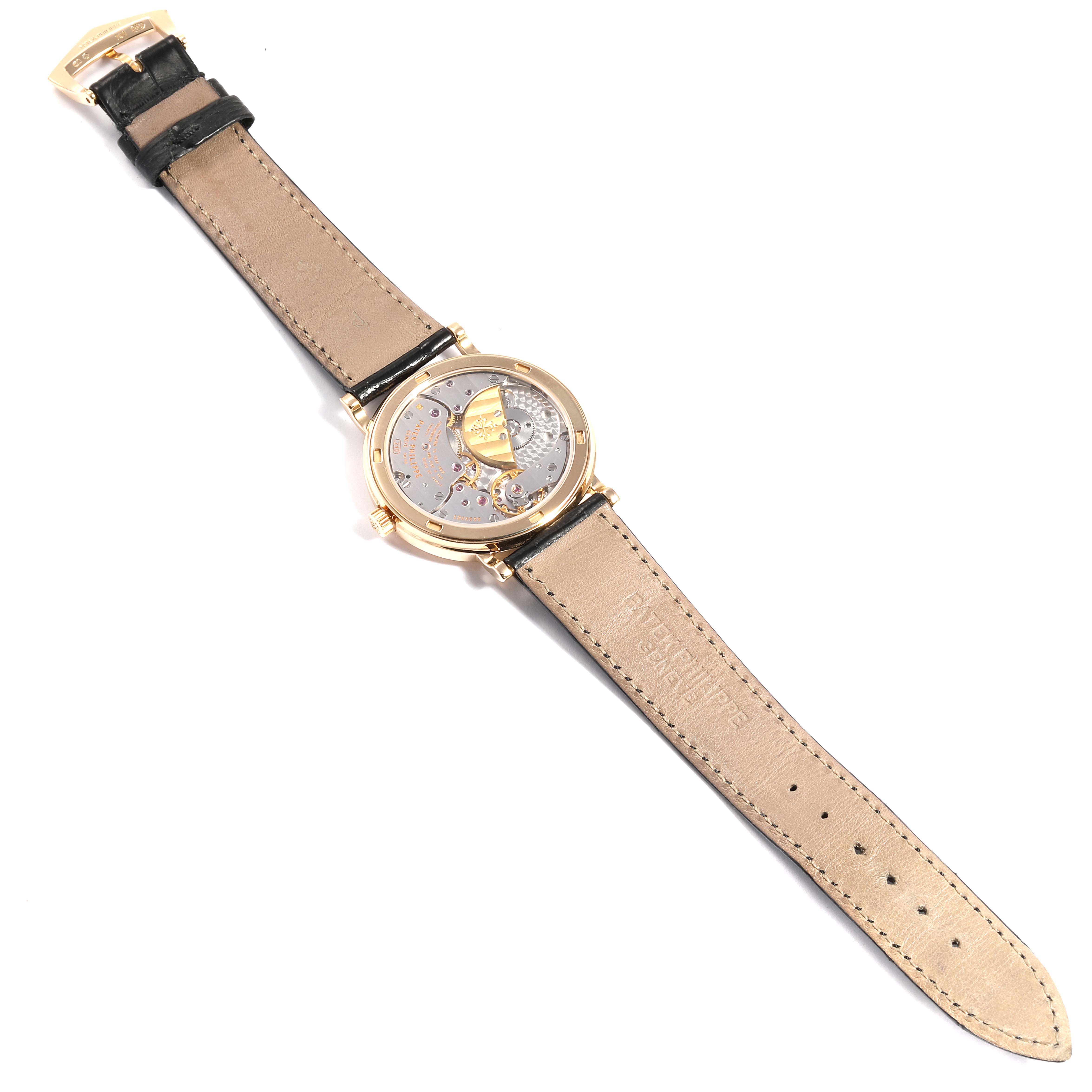 The image shows a Patek Philippe Calatrava 5120J Men's Yellow Gold White Dial 5120J Men's Yellow Gold White Dial watch from a top-down angle, displaying its open caseback and leather strap.