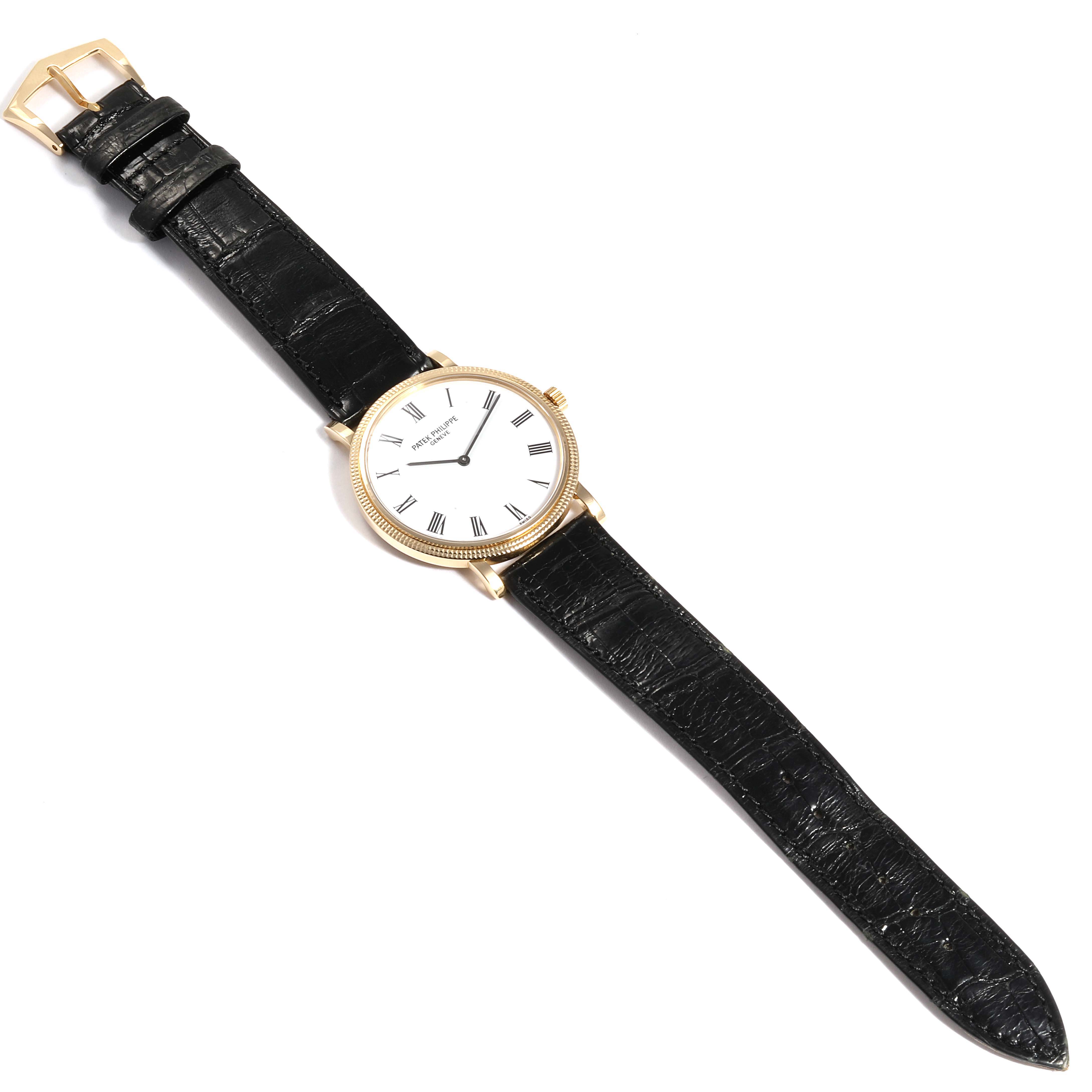 The image shows a Patek Philippe Calatrava 5120J Men's Yellow Gold White Dial 5120J Men's Yellow Gold White Dial watch from a top-down angle, displaying its black leather strap and round white dial with gold detailing.