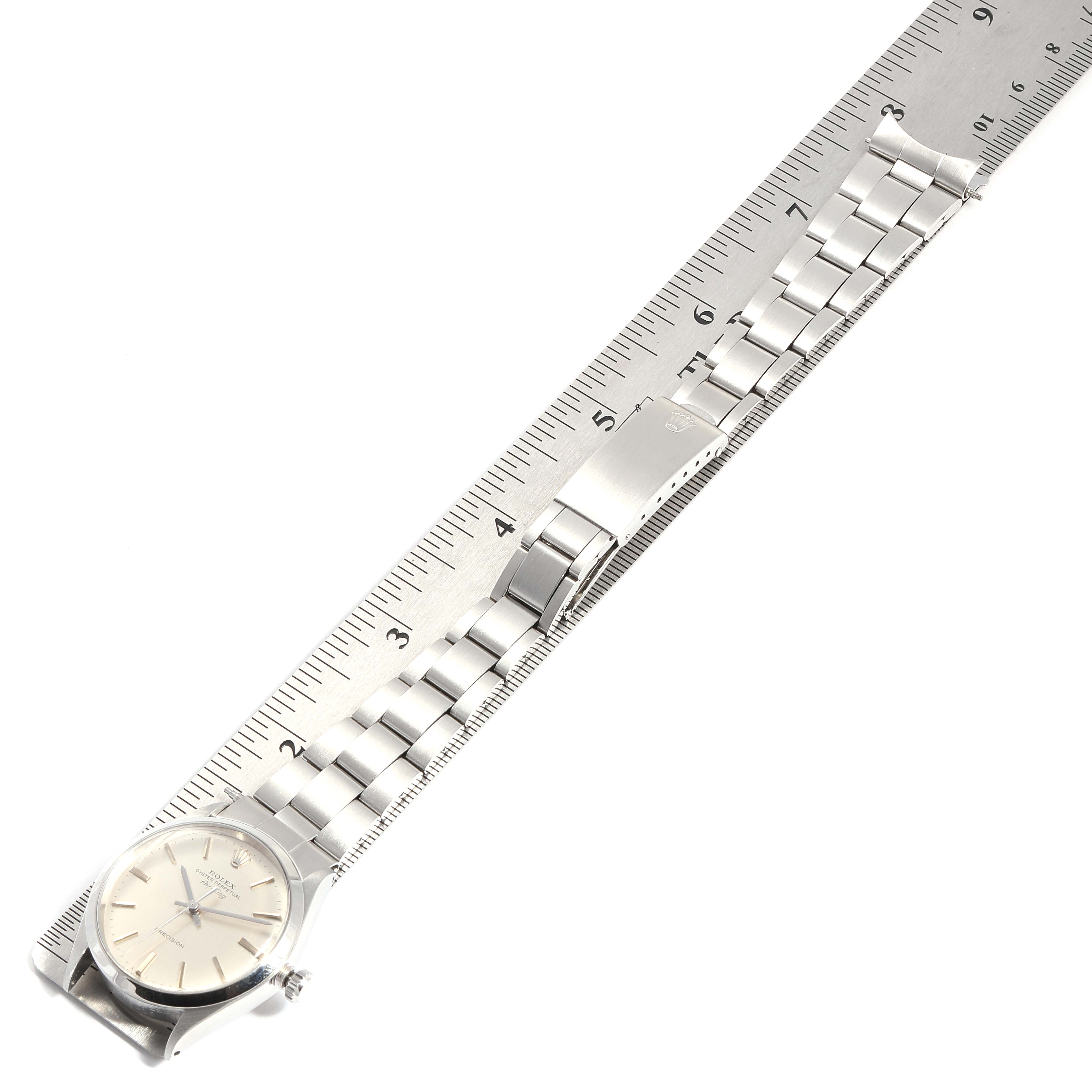 The Rolex Air-King 5500 Men's Stainless Steel Silver Dial 5500 Men's Stainless Steel Silver Dial watch is shown from a top view, displaying its face and entire metal bracelet laid against a ruler.