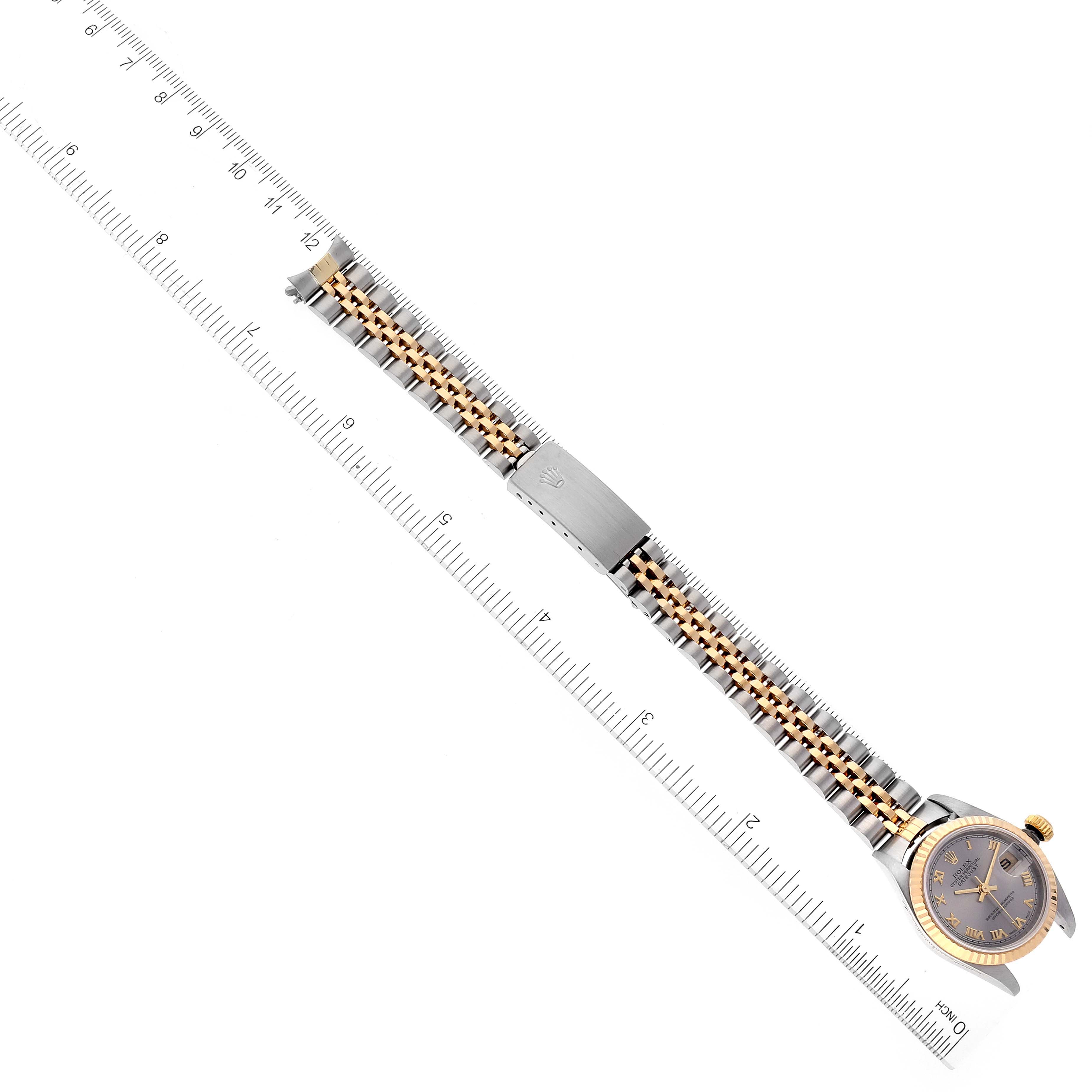 The image shows a top-down view of a Rolex Datejust 79173 Women
s Steel and Gold (two tone) Grey Dial 79173 Women
s Steel and Gold (two tone) Grey Dial watch, highlighting its bracelet and clasp alongside a ruler for scale.