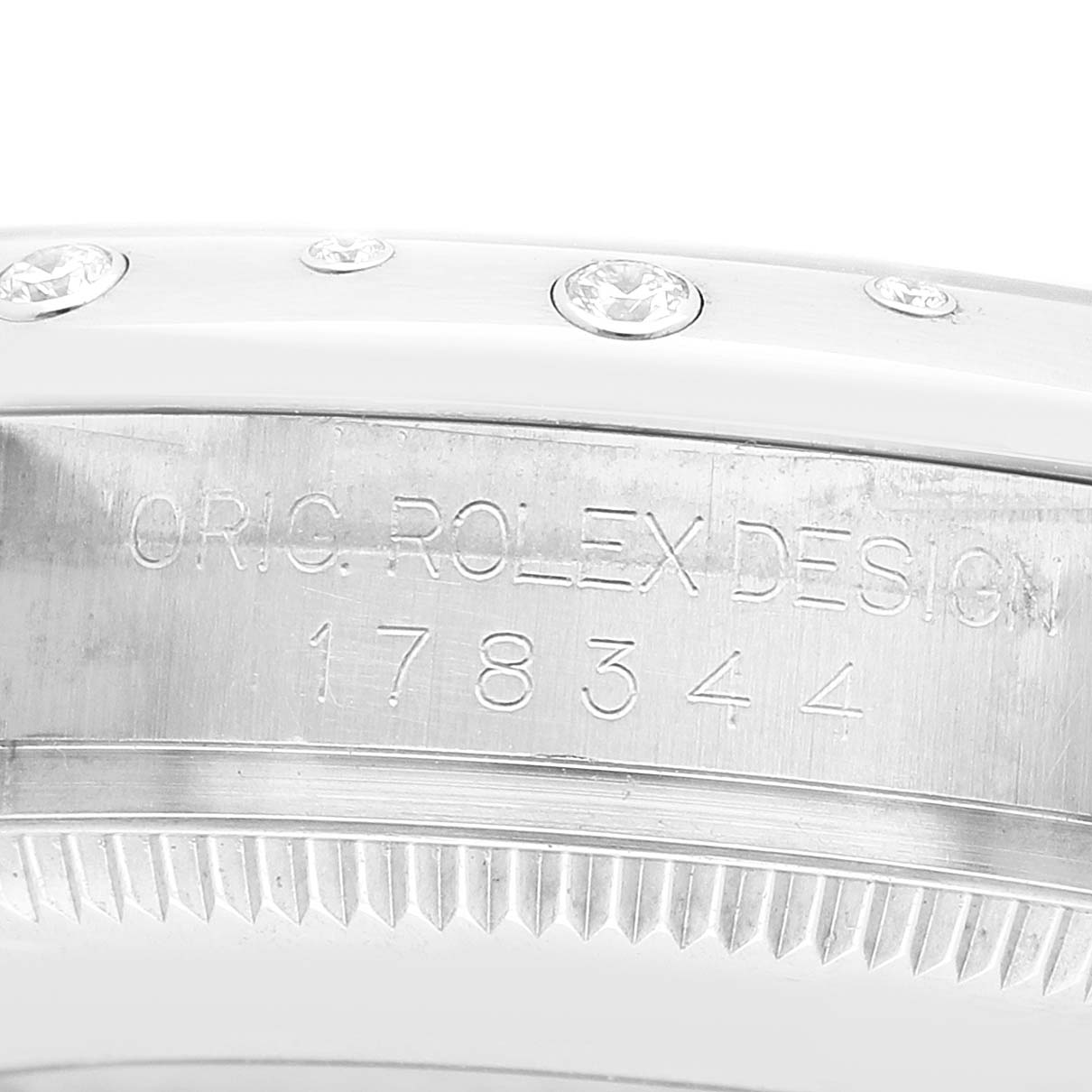 The image shows a close-up of the Rolex Mid-Size 178344 Women's Stainless Steel Black Dial model's engraved case side and part of its diamond-set bezel.