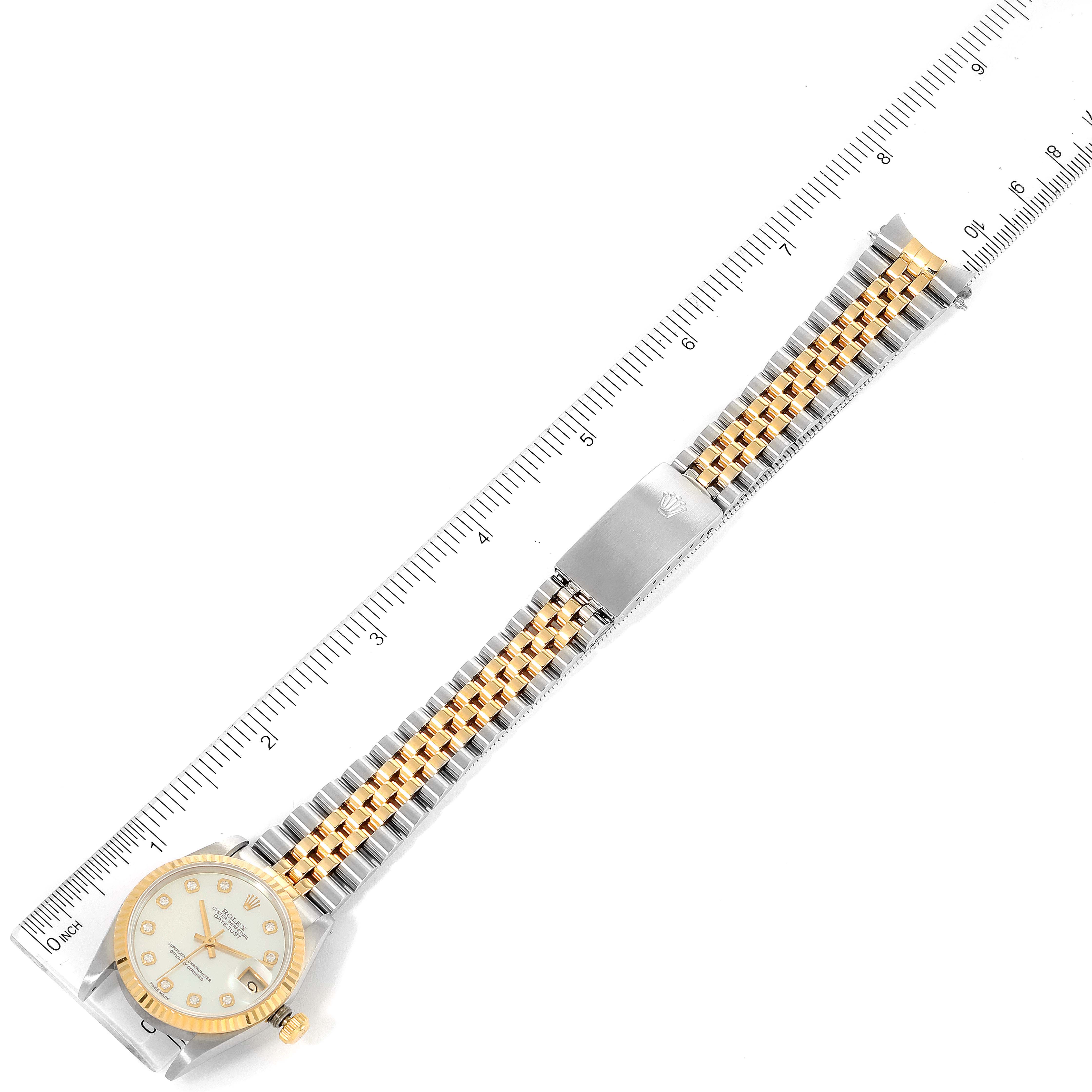 This image shows a top-down view of a Rolex Mid-Size 68273 Women's Steel and Gold (two tone) Mother of Pearl Dial 68273 Women's Steel and Gold (two tone) Mother of Pearl Dial model watch with its full bracelet and clasp extended and rulers for scale.