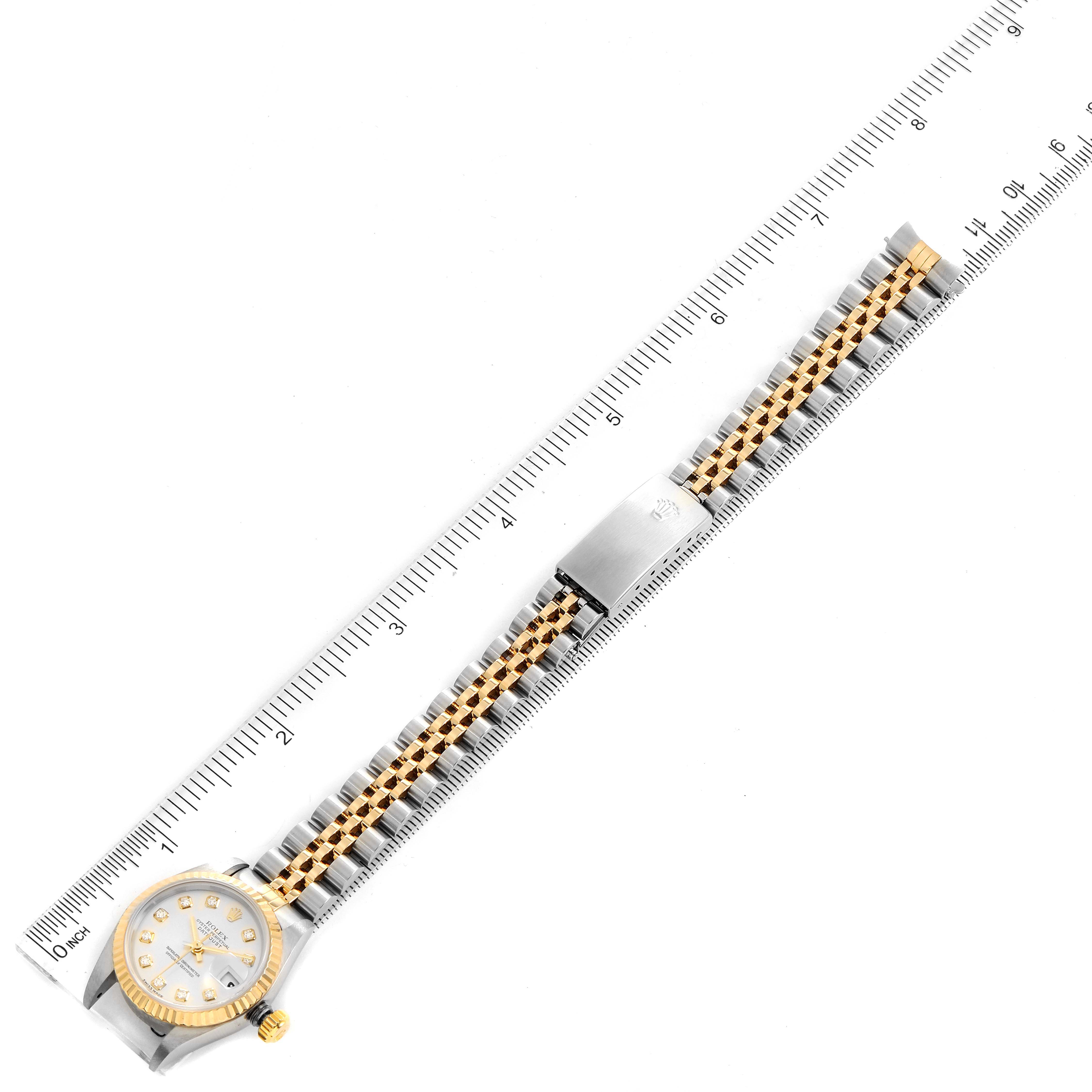 The image shows a top-down view of a Rolex Datejust 79173 Women
s Steel and Gold (two tone) Silver Dial 79173 Women
s Steel and Gold (two tone) Silver Dial watch, including its dial, bezel, and jubilee bracelet, alongside a ruler for measurement.