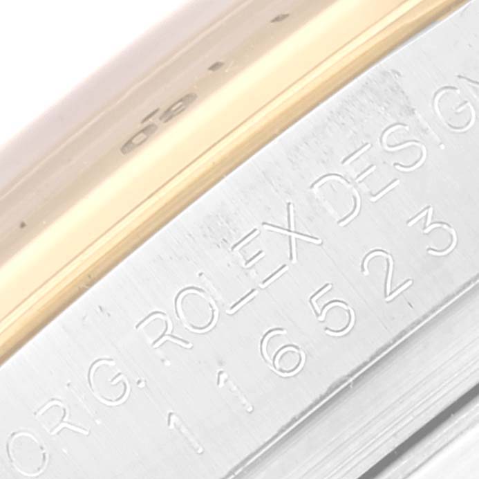 The image shows a close-up of the Rolex Daytona 116523 Men
s Steel and Gold (two tone) Black Dial 116523 Men
s Steel and Gold (two tone) Black Dial model, focusing on the engraved text on its side.