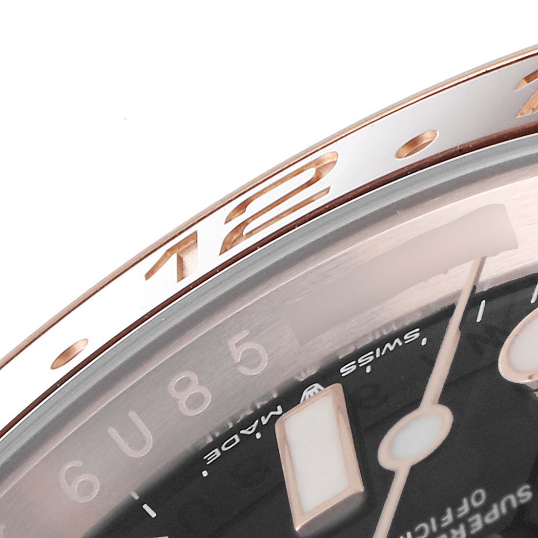 This close-up of the Rolex GMT-Master 126715 Men's Rose Gold Black Dial 126715 Men's Rose Gold Black Dial watch shows the bezel and part of the watch face with hour markers.
