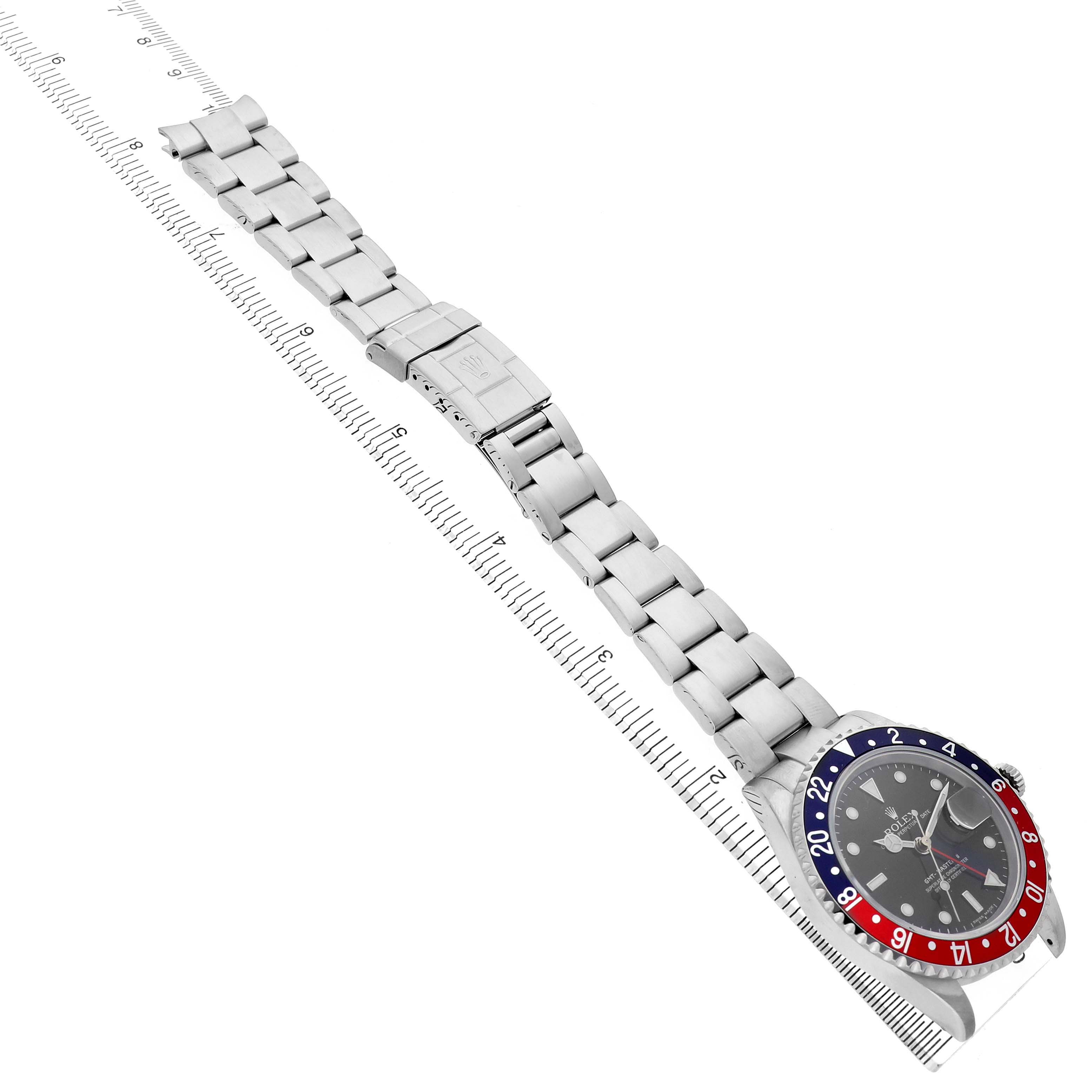 The Rolex GMT-Master 16710 T Men's Stainless Steel Black Dial watch is shown at an angle featuring the bezel, dial, bracelet, and clasp with a ruler for scale.