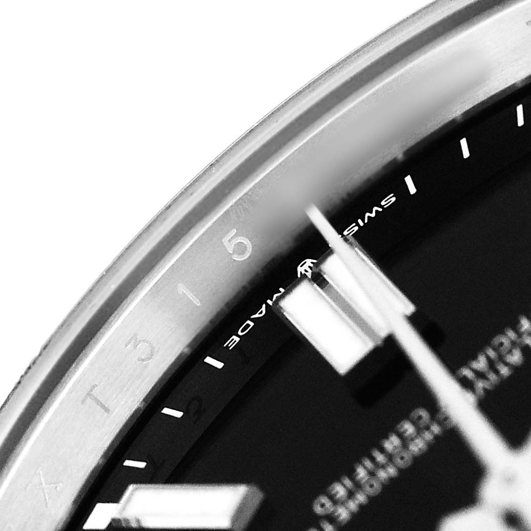 The image shows a close-up of the bezel and part of the dial of a Rolex Oyster Perpetual M124300-0002 Men's Stainless Steel Black Dial watch.