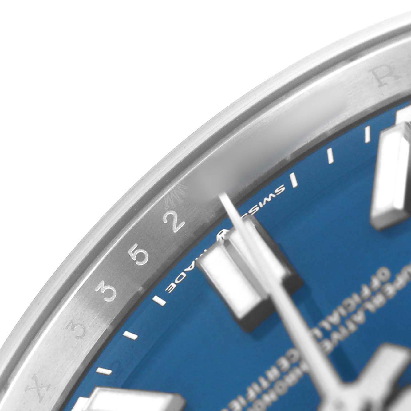 The image shows a close-up of the dial and bezel of a Rolex Oyster Perpetual 134300 Men's Stainless Steel Blue Dial watch, highlighting numerals and part of the blue face.
