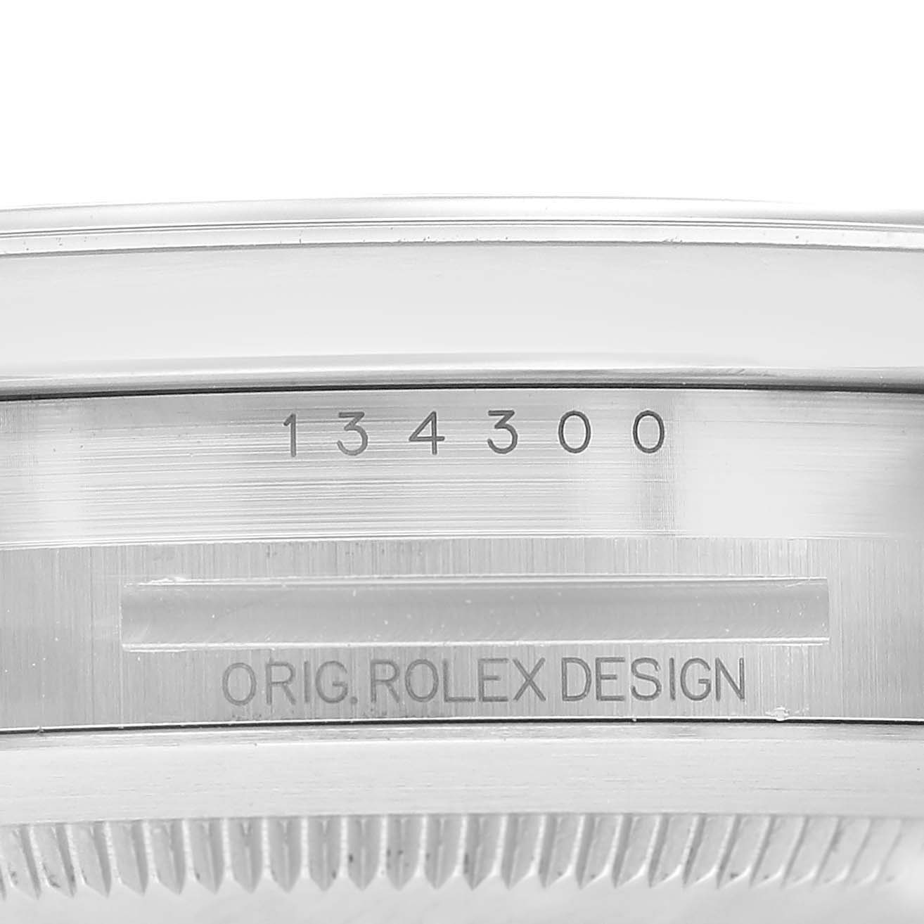 The image shows a close-up of the casing edge of the Rolex Oyster Perpetual 134300 Men's Stainless Steel Blue Dial, including the model number and design inscription.