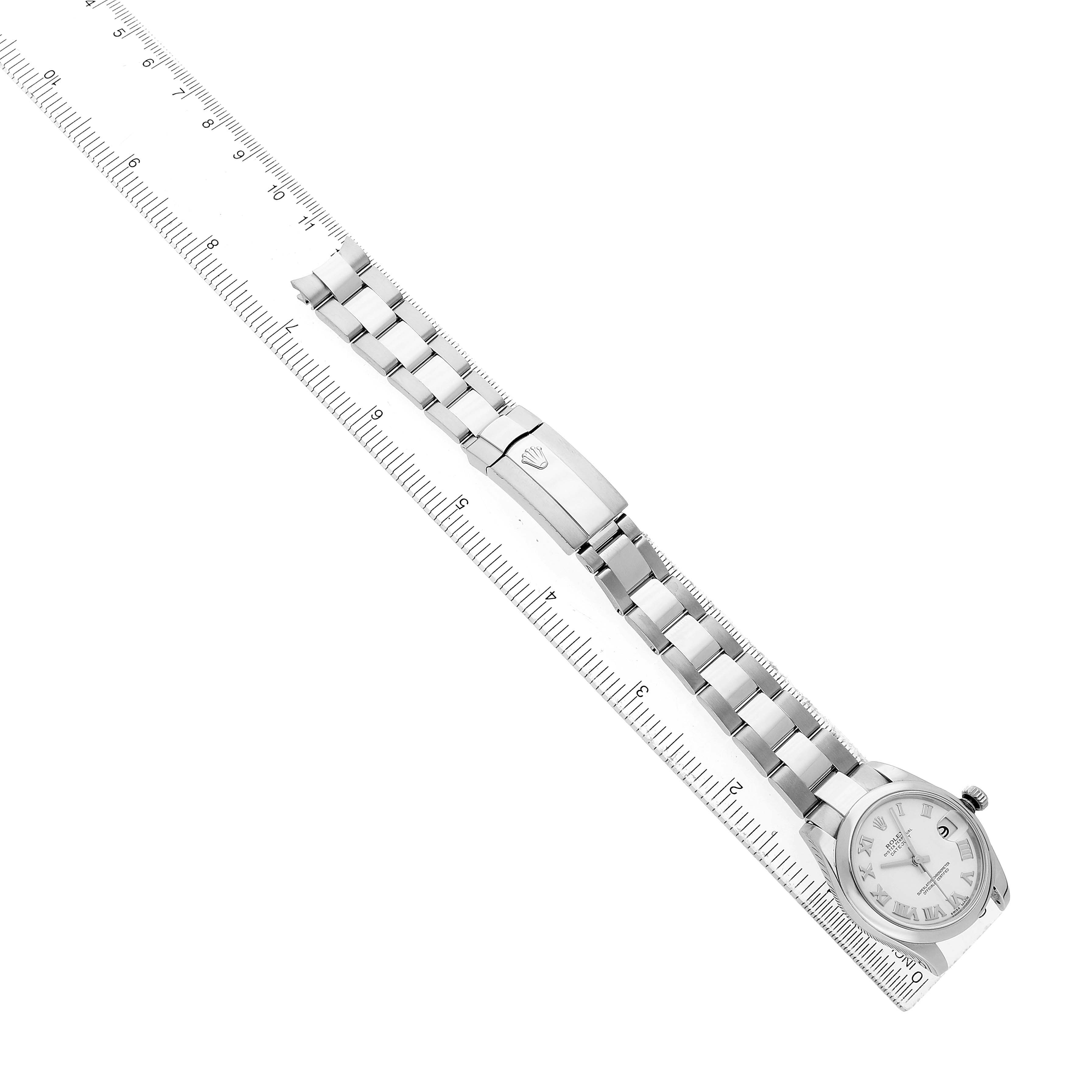 The Rolex Oyster Perpetual 77080 Women's Stainless Steel Silver Dial watch is shown from an oblique angle, highlighting the bracelet, clasp, and face beside a ruler.