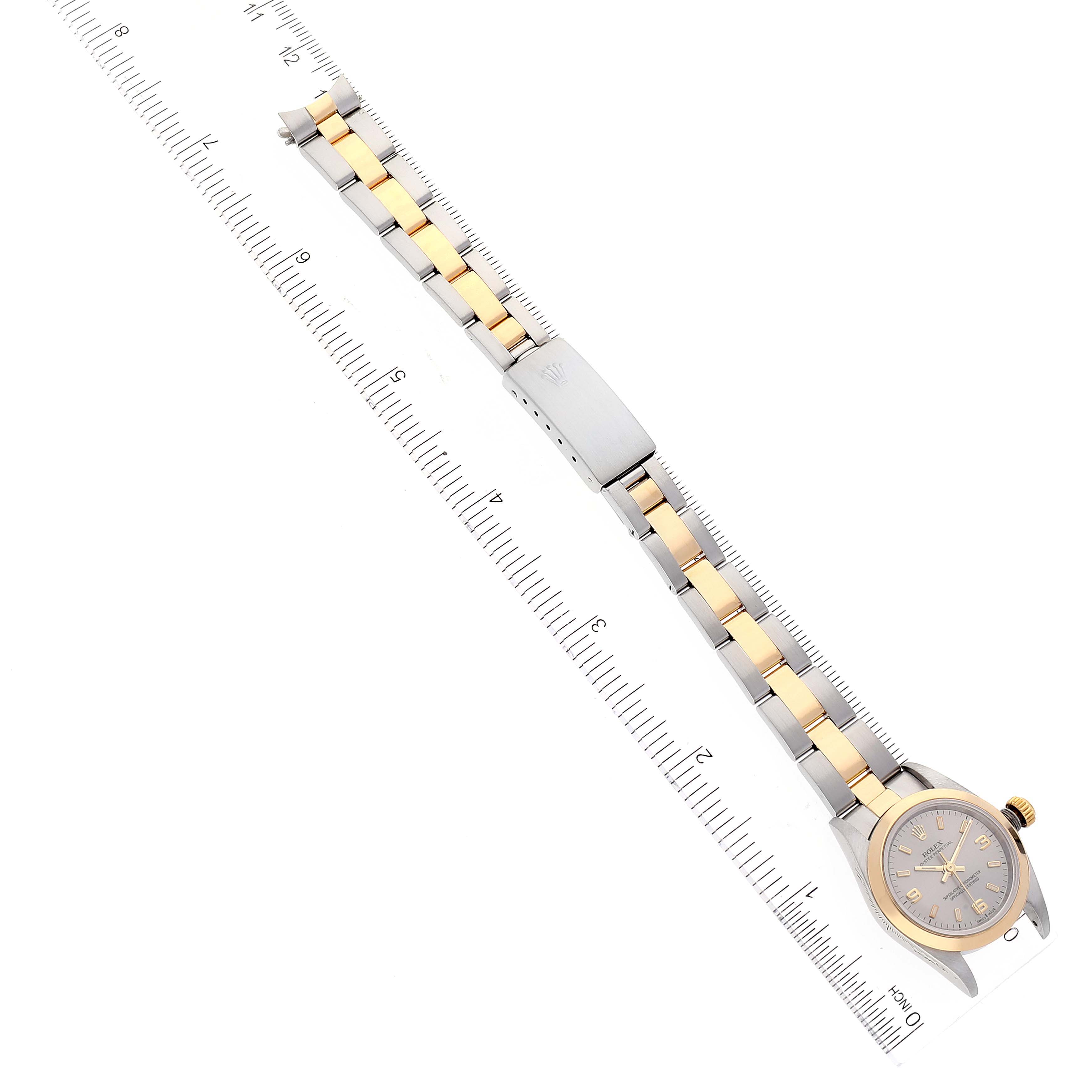 The image shows a Rolex Oyster Perpetual 76183 Women's Steel and Gold (two tone) Grey Dial 76183 Women's Steel and Gold (two tone) Grey Dial watch positioned flat with its two-tone bracelet stretched out next to a ruler.