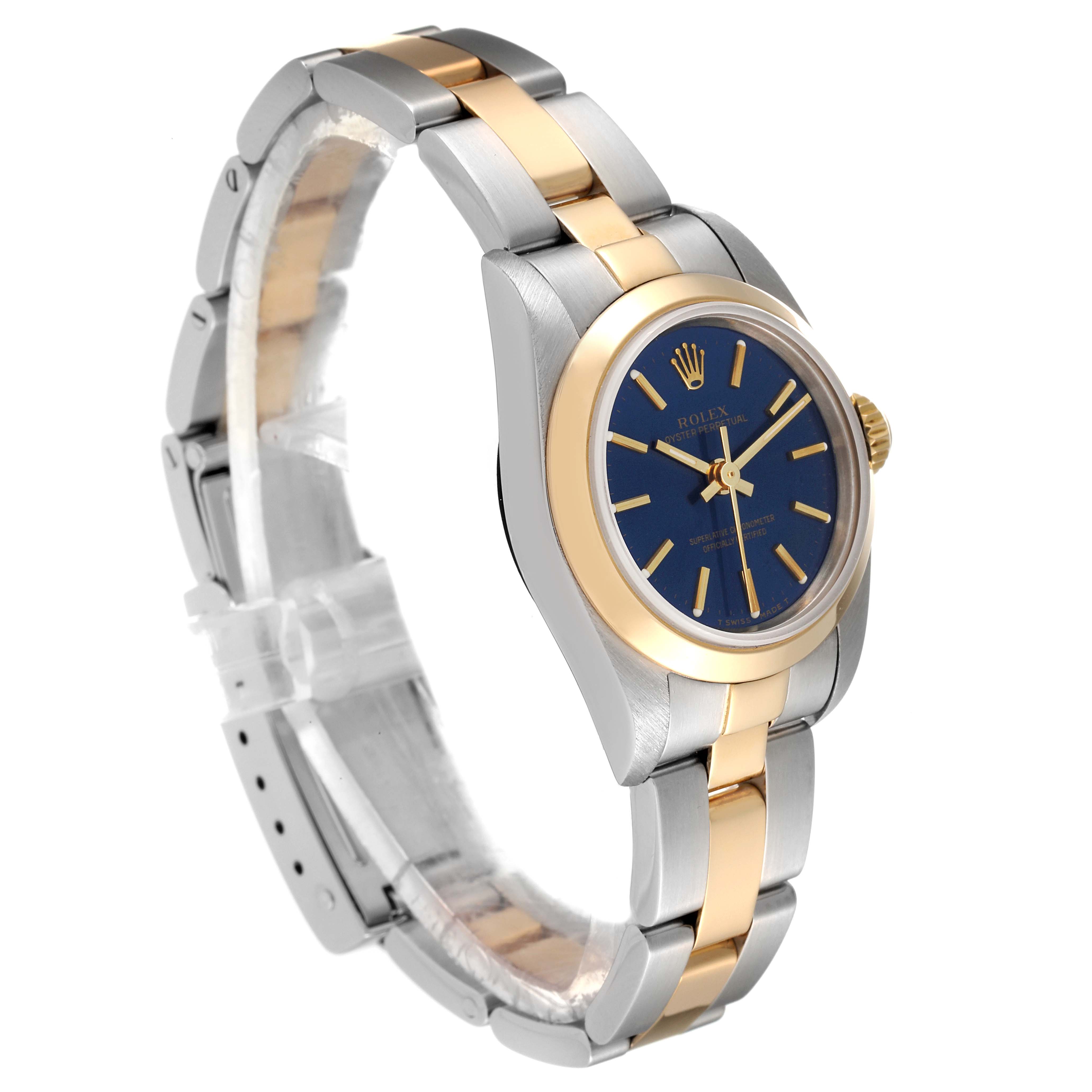 The Rolex Oyster Perpetual 67183 Women
s Steel and Gold (two tone) Blue Dial 67183 Women
s Steel and Gold (two tone) Blue Dial watch is shown at a three-quarter angle, highlighting its blue dial, gold bezel, and two-tone metal bracelet.