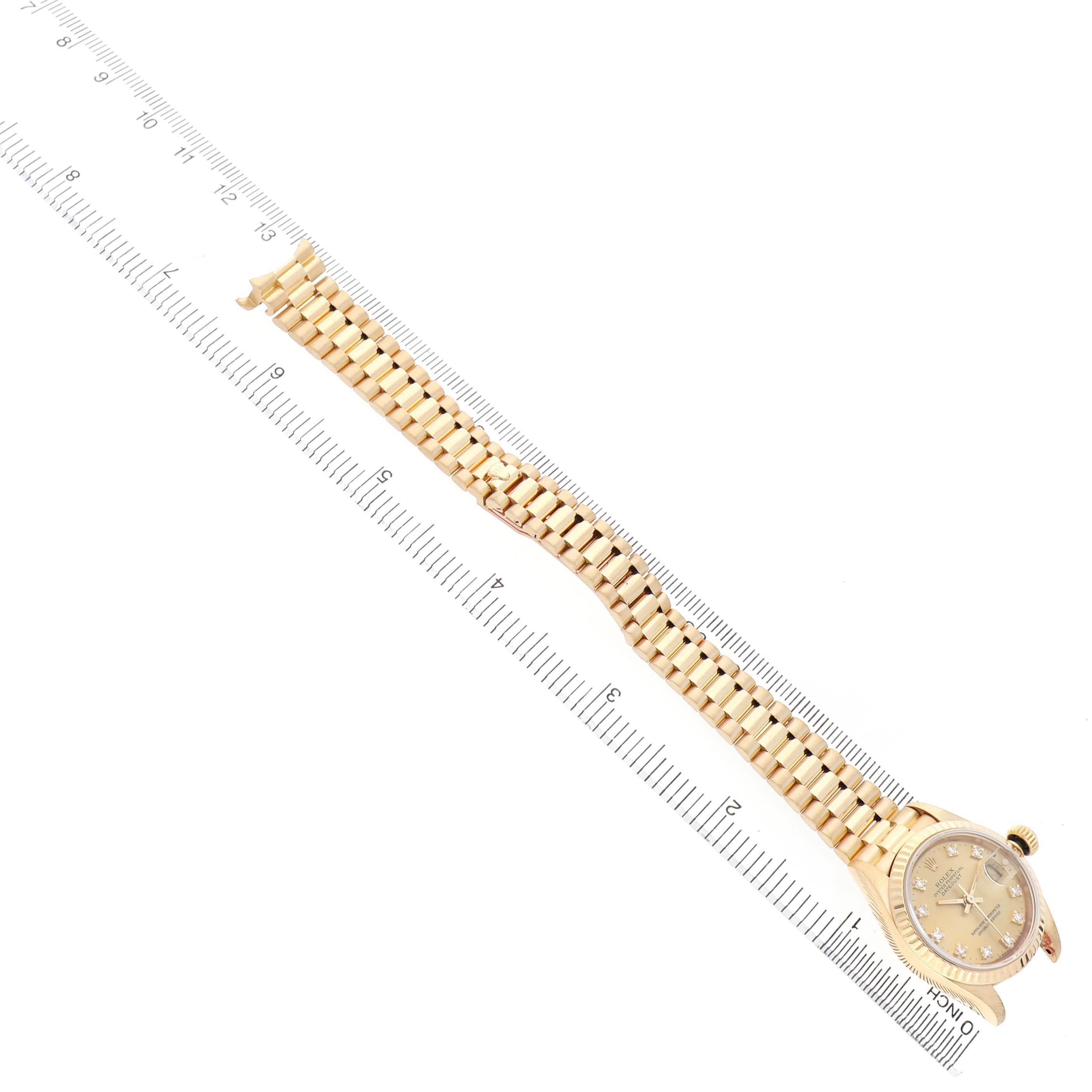 The Rolex Datejust 69178 Women's Yellow Gold Champagne Dial watch is shown at an angle with its bracelet fully extended alongside a ruler.