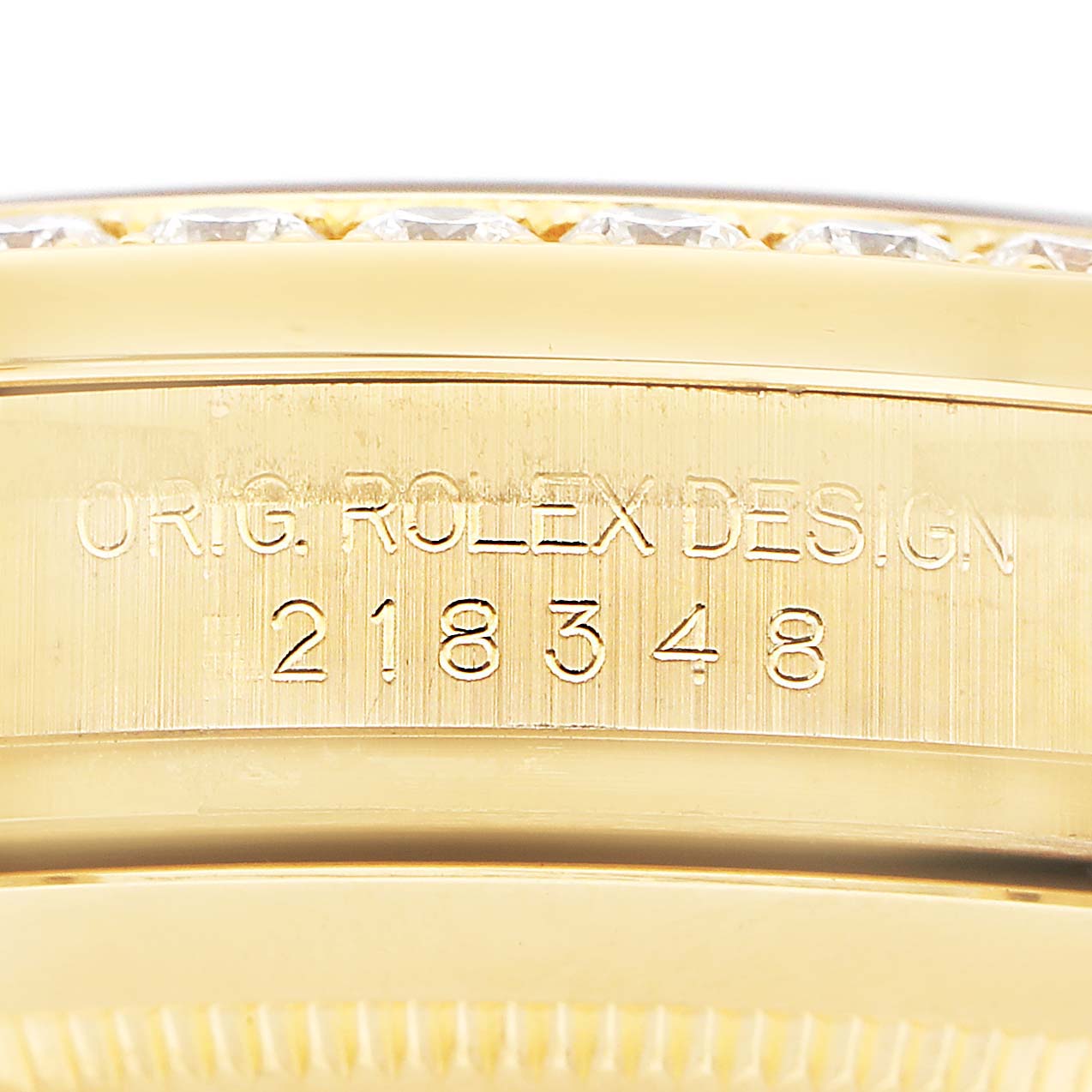 The image shows a close-up of the Rolex President 218348 Men's Yellow Gold Champagne Dial model's engraved bezel with serial numbers.