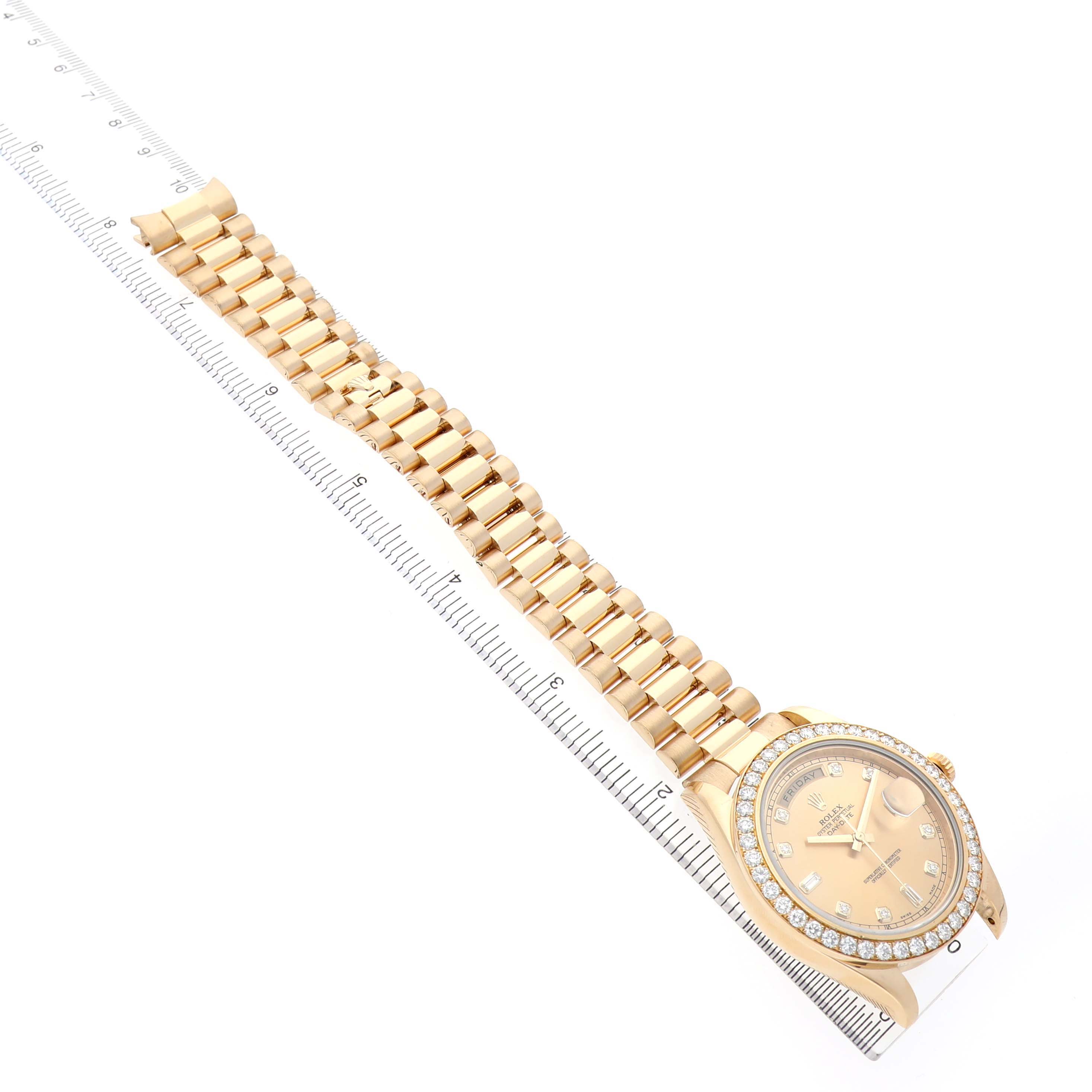 The Rolex President 218348 Men's Yellow Gold Champagne Dial model watch is shown from an angled top view, highlighting its face, bezel, and full bracelet alongside a ruler.