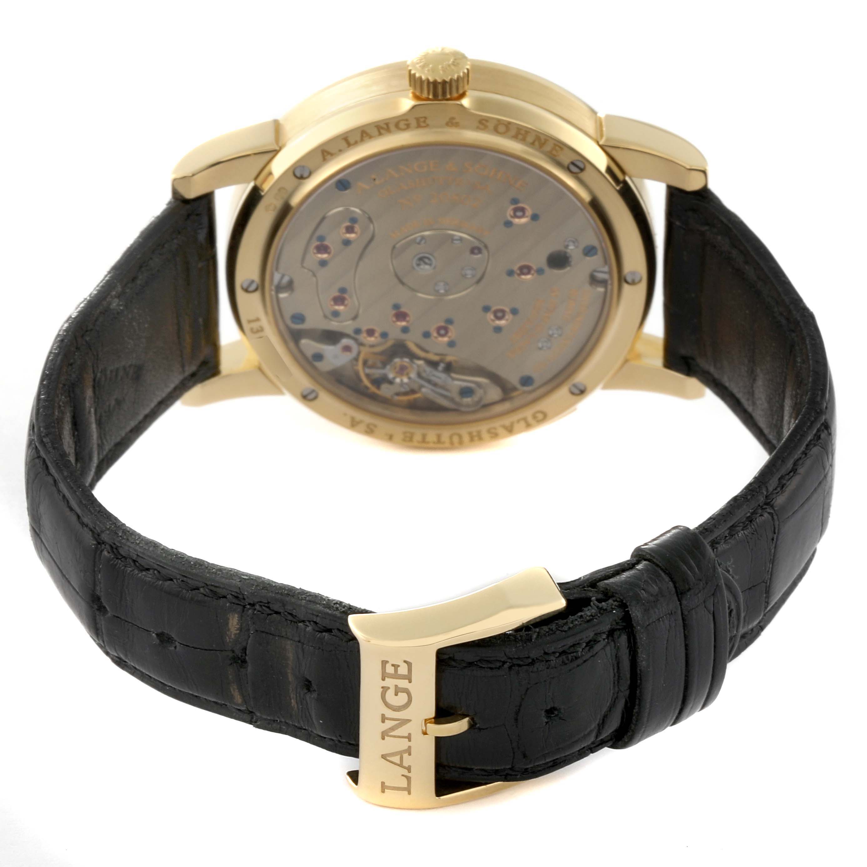The image shows the back view of a Lange 1 watch by A. Lange & Söhne, highlighting the movement through the case back and the clasp.
