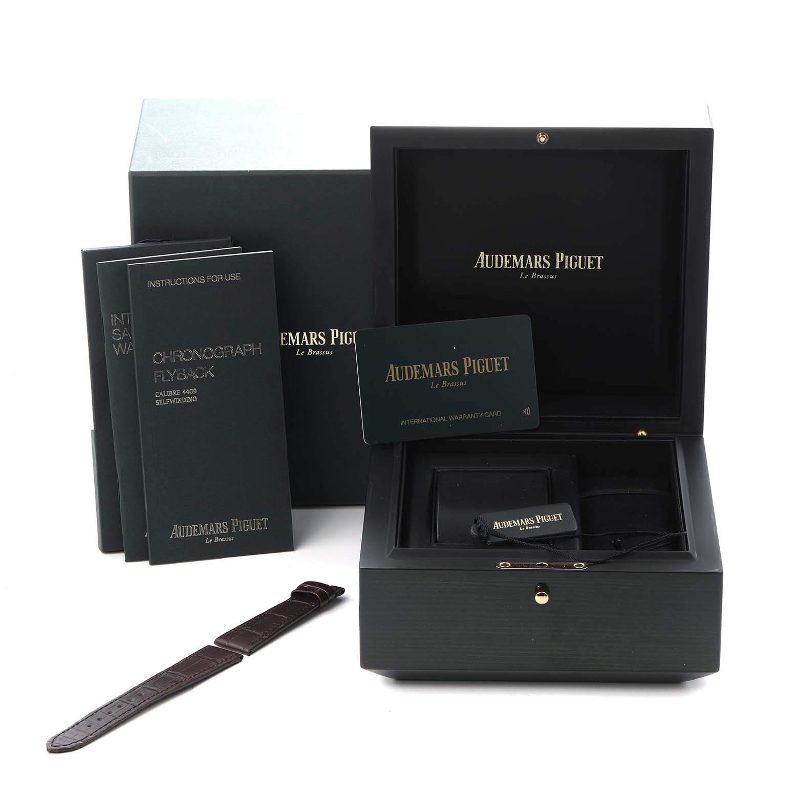 The image shows a Remaster model by Audemars Piguet, with its open box, warranty card, manuals, and a separate watch strap.