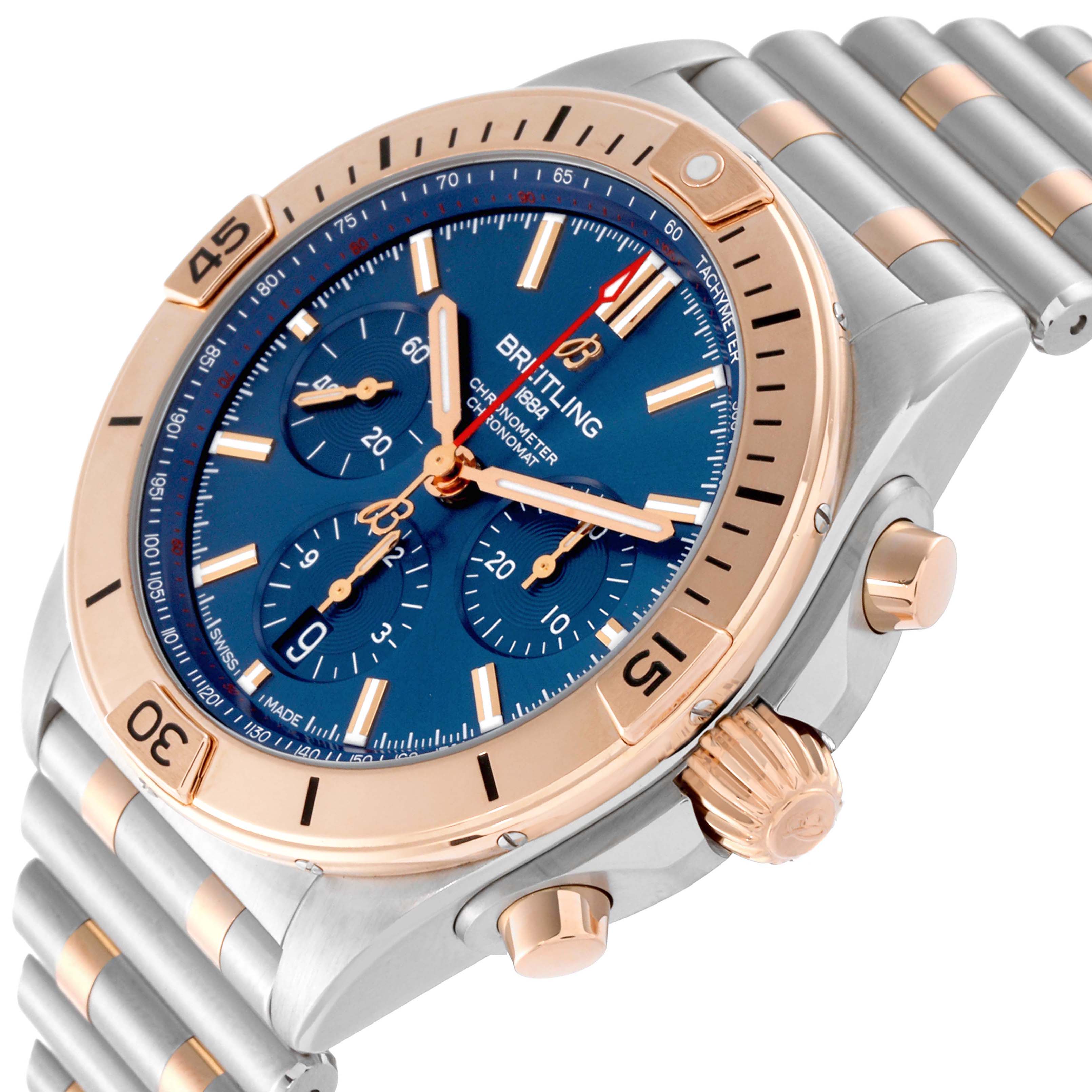 The Breitling Chronomat UB0134101C1U1 Men's Steel and Gold (two tone) Blue Dial watch is shown at an angled side view, highlighting its blue dial, bezel, crown, and bracelet.