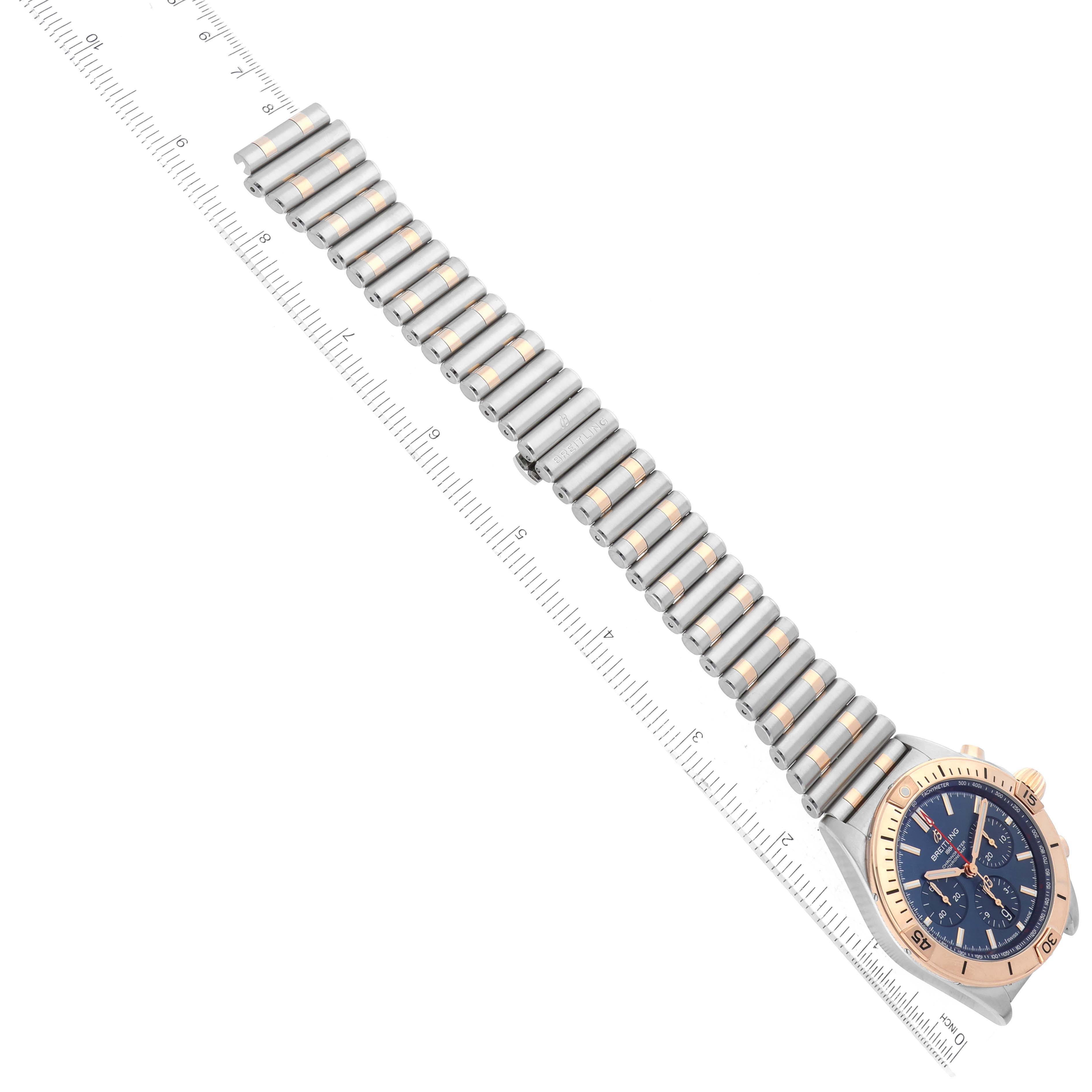 The image shows a Breitling Chronomat UB0134101C1U1 Men's Steel and Gold (two tone) Blue Dial UB0134101C1U1 Men's Steel and Gold (two tone) Blue Dial watch at a slight angled view, including the full bracelet and a partially visible ruler.
