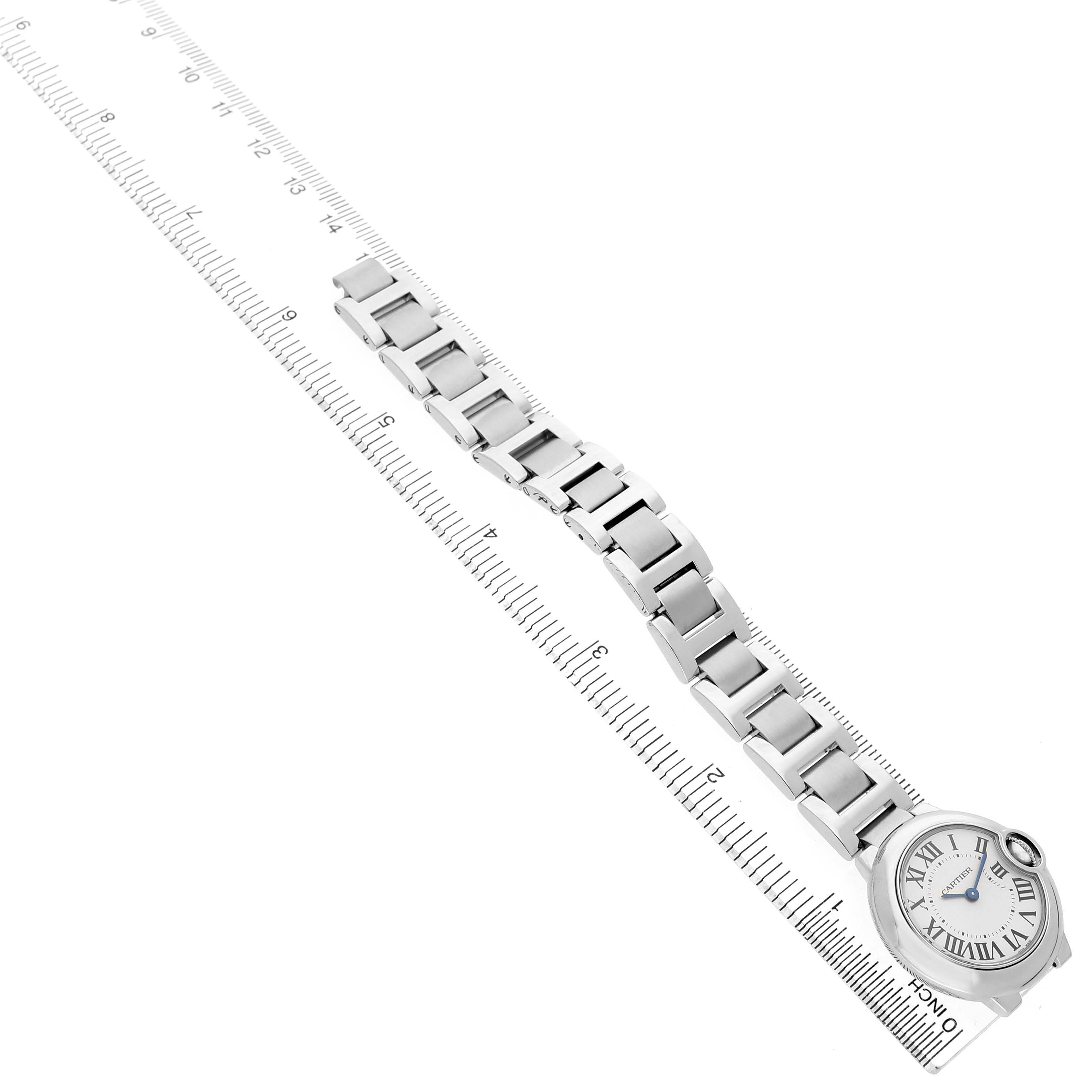 The Cartier Ballon Bleu W69010Z4 Women's Stainless Steel Silver Dial watch is shown from a top angle, highlighting the face and metal bracelet alongside a ruler.