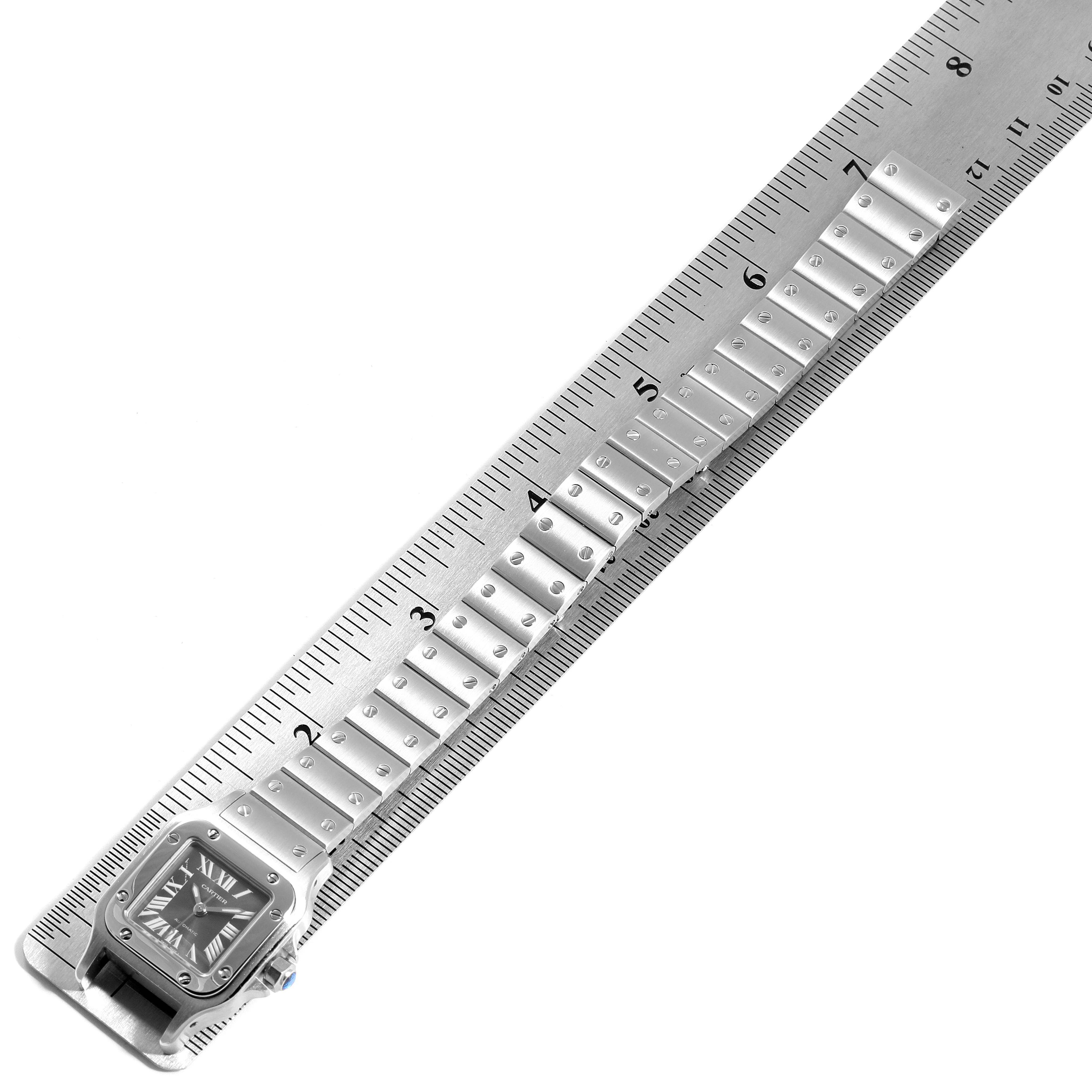 The image shows a Cartier Santos W20066D6 Women's Stainless Steel Grey Dial W20066D6 Women's Stainless Steel Grey Dial watch at an angled top-down view, aligned next to a ruler displaying its metal bracelet.