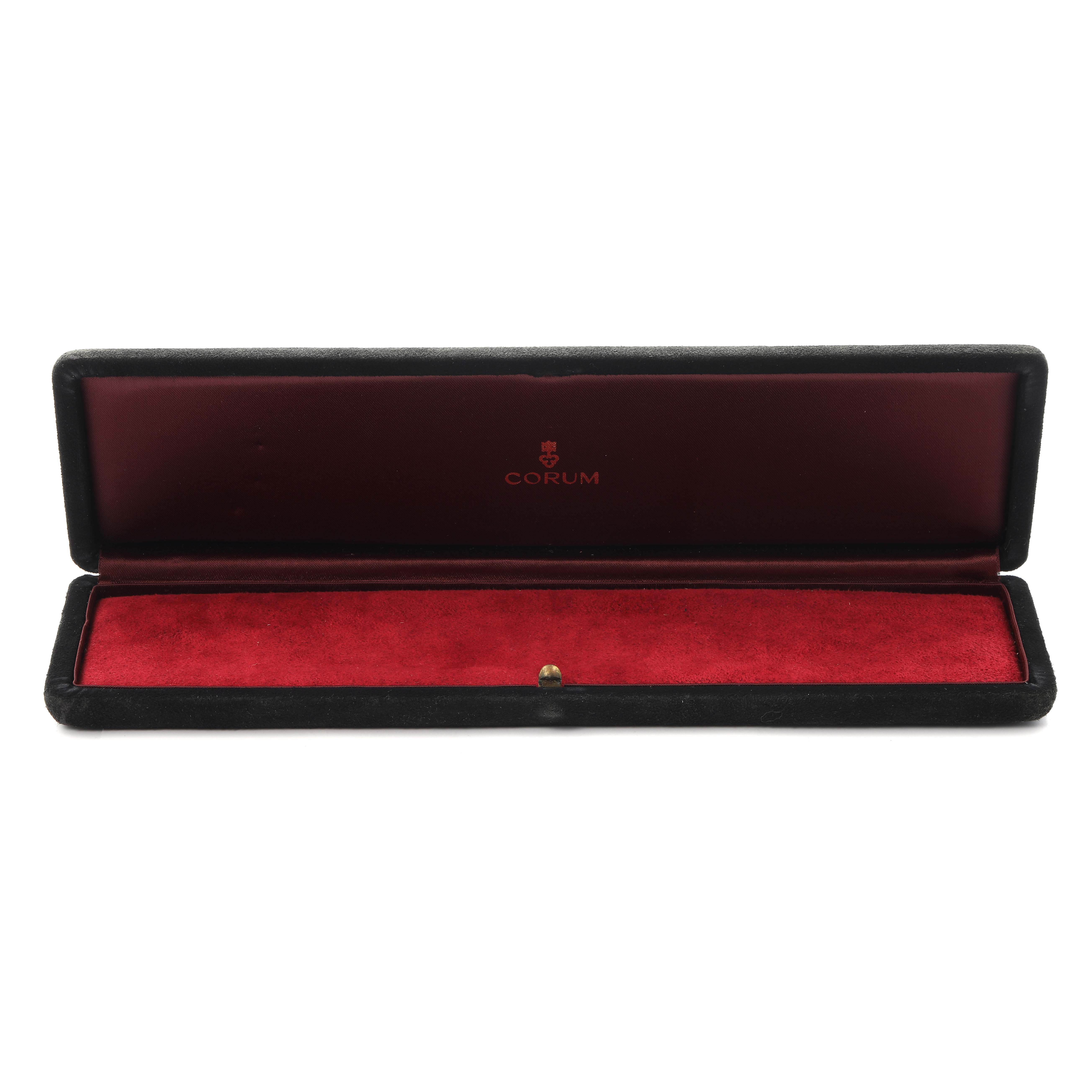 The image shows an open Corum watch box, likely for a Coin Watch model, with a plush red interior and Corum branding.
