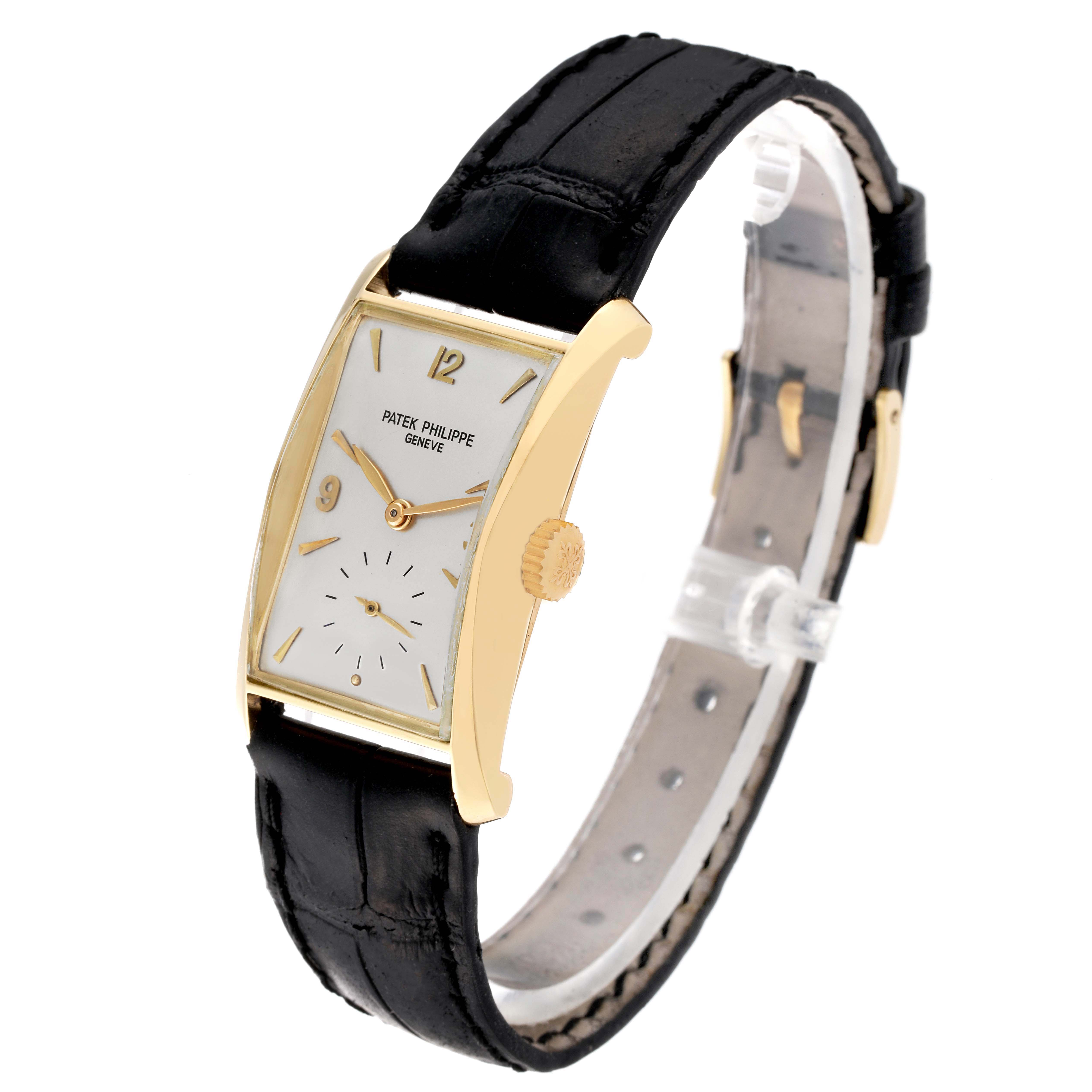 The Patek Philippe Vintage 2468 Men's Yellow Gold Silver Dial watch is shown at an angled side view, highlighting its rectangular dial, gold crown, and black leather strap.