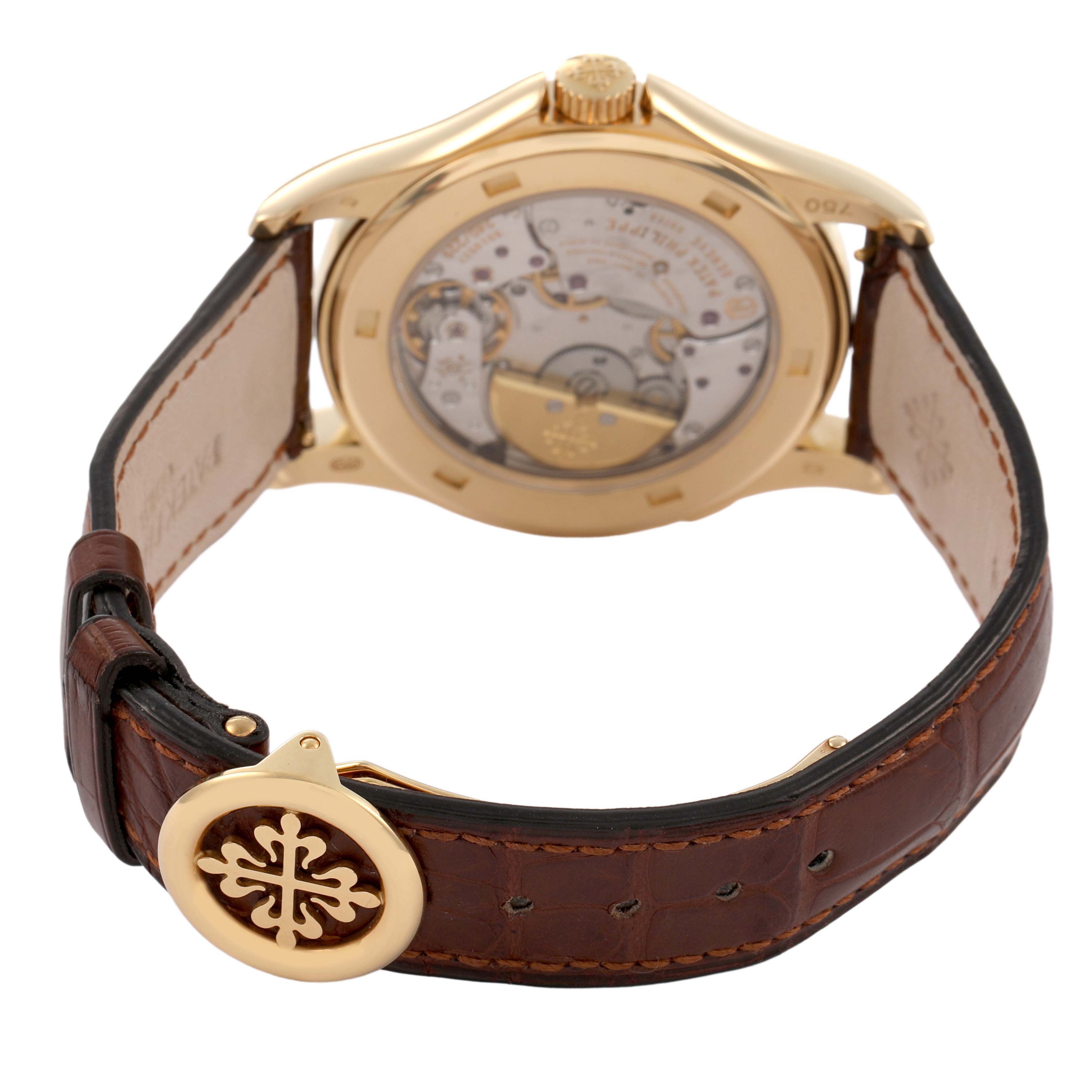 The image shows the back view of the Patek Philippe Complications 5131J-001 Men's Yellow Gold Silver Dial watch, displaying its movement and brown leather strap.