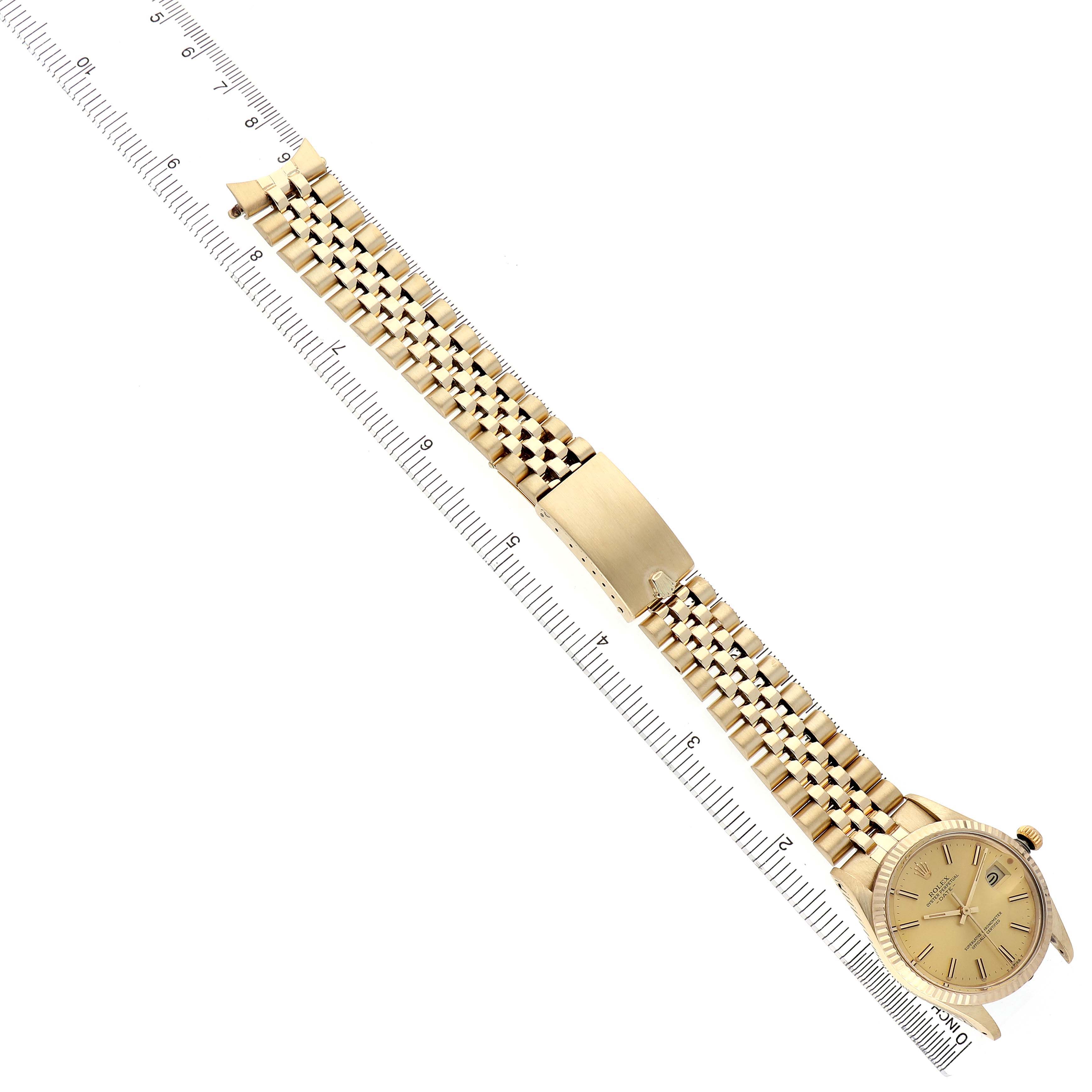 The Rolex Date 15037 Men's Yellow Gold Champagne Dial watch is shown diagonally, displaying the full bracelet, clasp, and face against a ruler for scale.