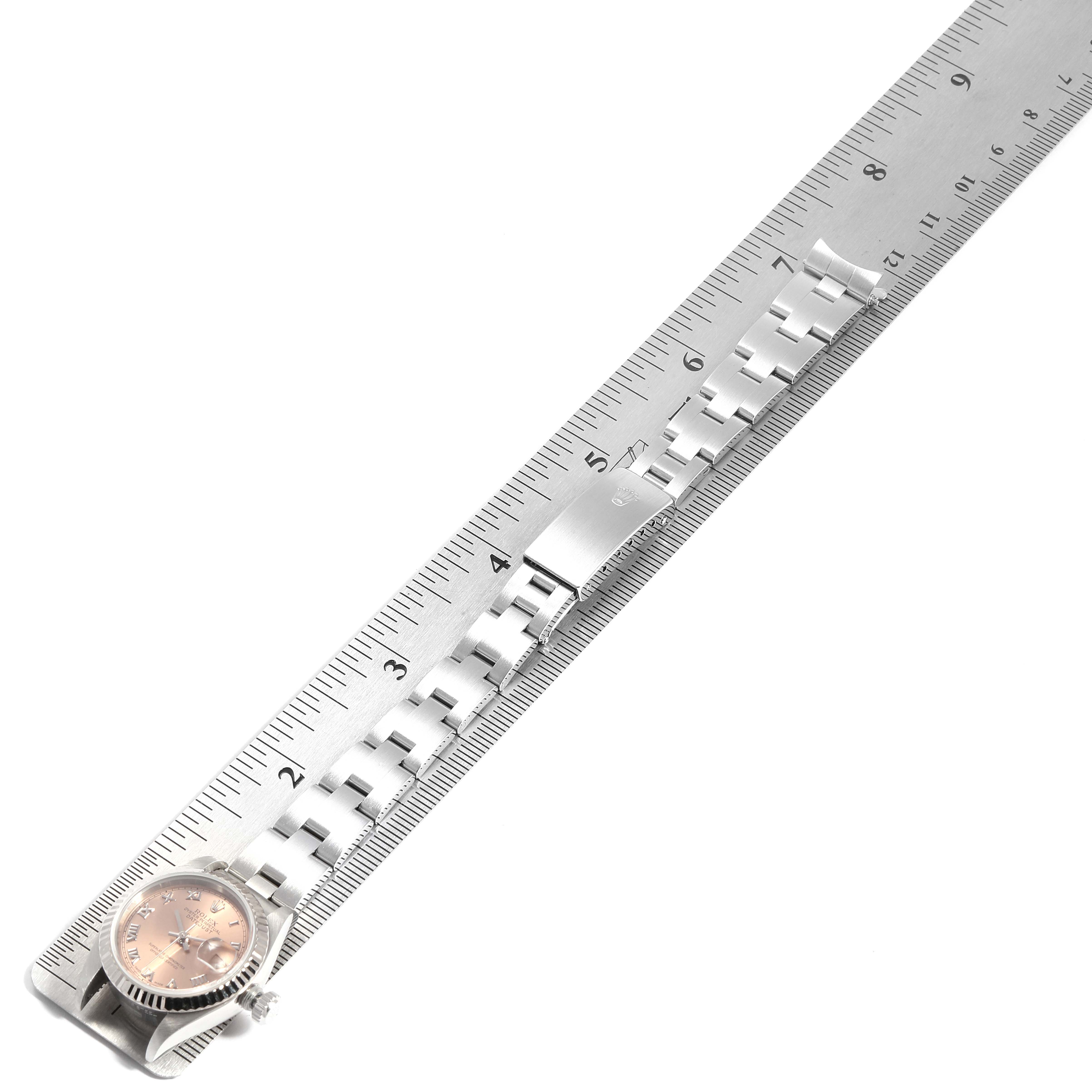 The image shows a Rolex Datejust 69174 Women's Stainless Steel Pink Dial 69174 Women's Stainless Steel Pink Dial watch placed along a ruler, highlighting the face, bezel, and metal strap.