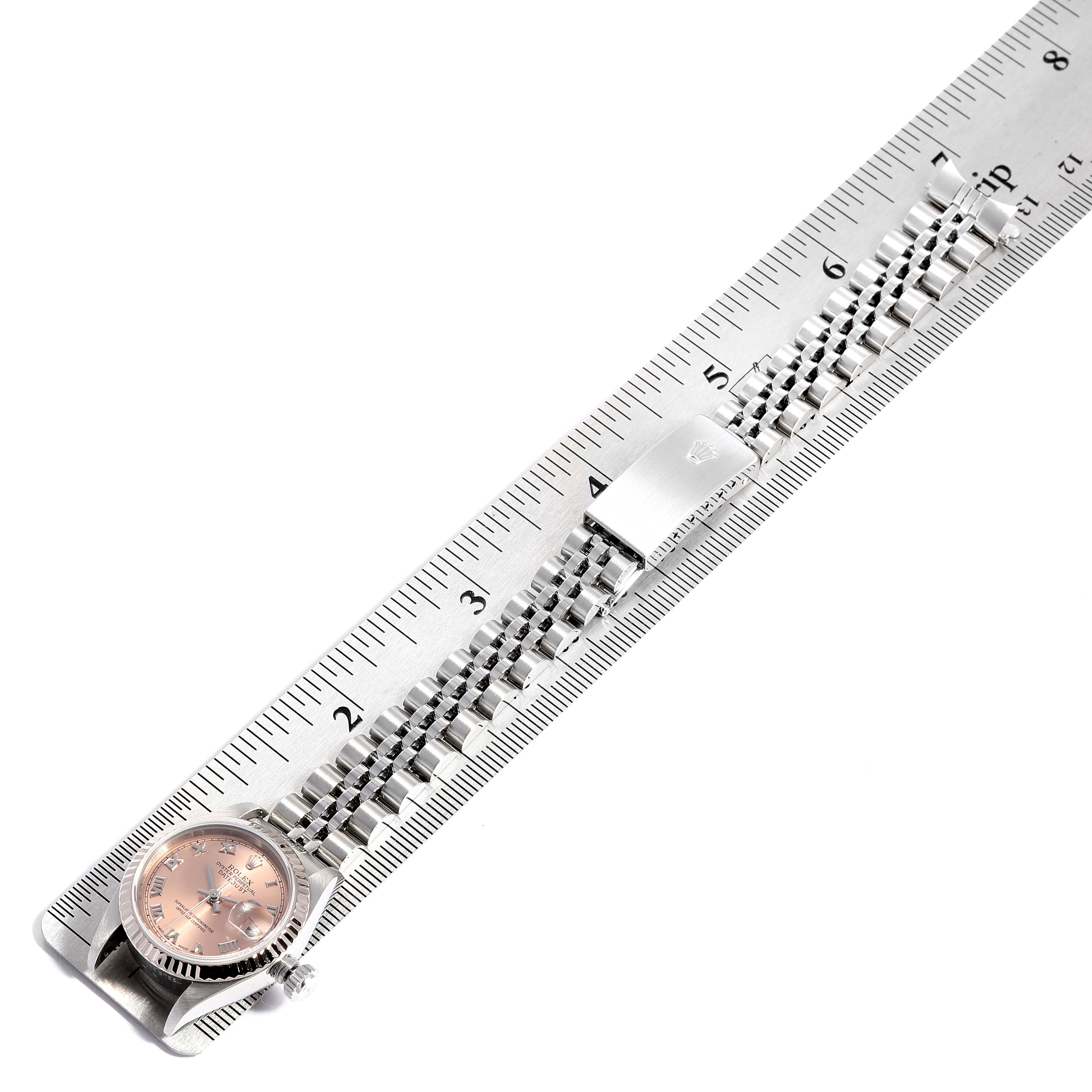 The Rolex Datejust 79174 Women's Stainless Steel Pink Dial 79174 Women's Stainless Steel Pink Dial watch is shown from an overhead angle with its bracelet measured alongside a ruler.