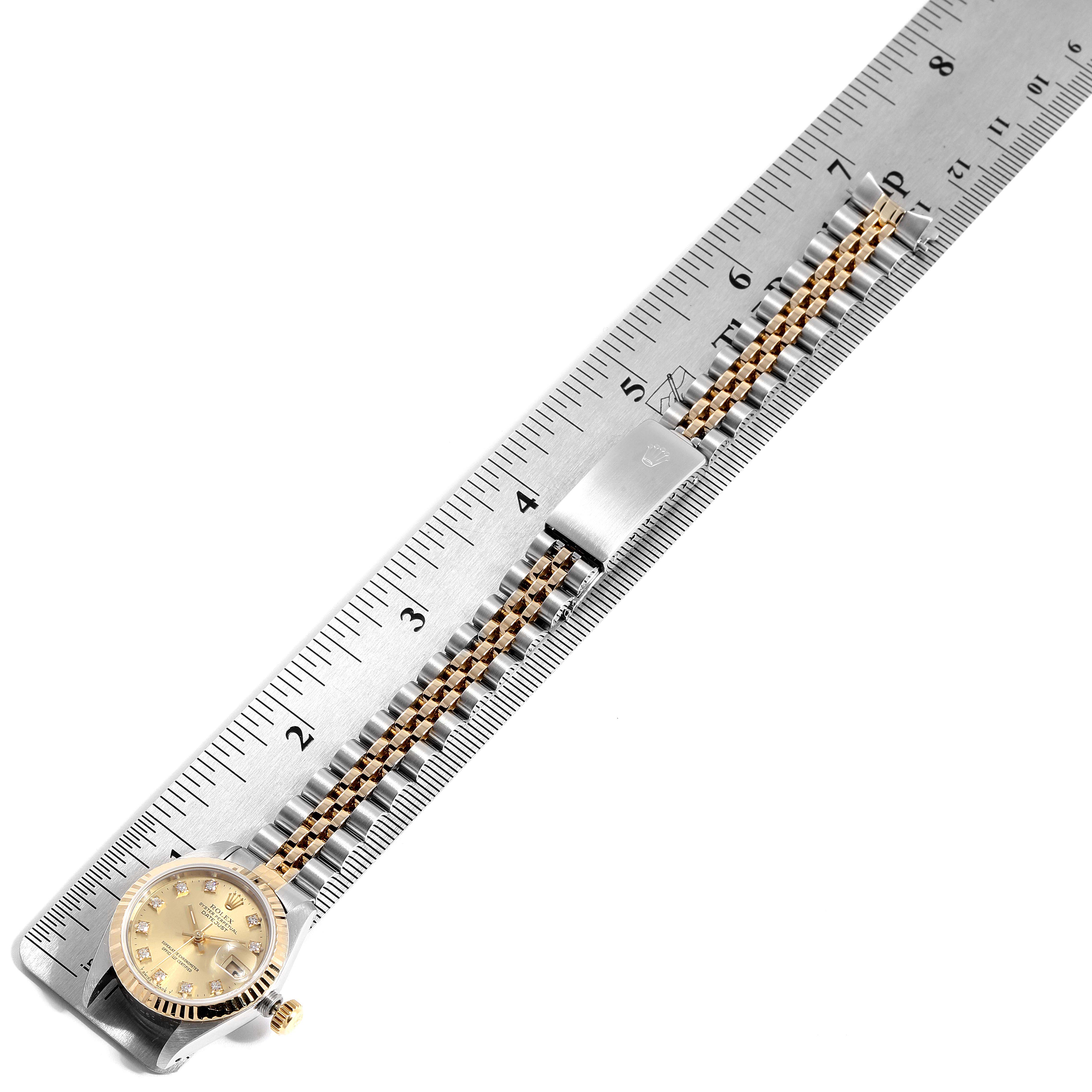 This image shows a top-down view of a Rolex Datejust 69173 Women
s Steel and Gold (two tone) Champagne Dial 69173 Women
s Steel and Gold (two tone) Champagne Dial watch next to a ruler, highlighting the dial, case, and bracelet.