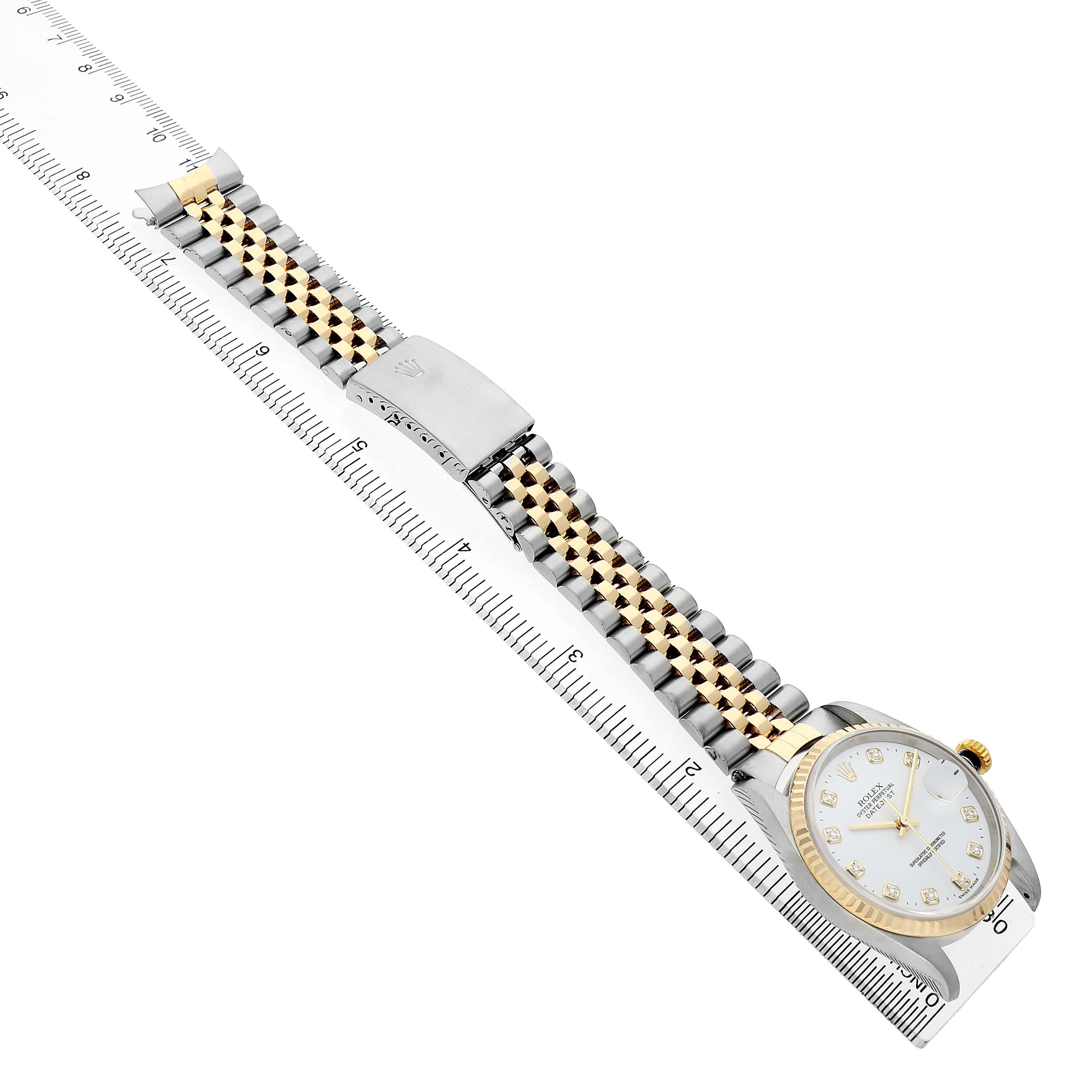 The Rolex Datejust 16233 Men's Steel and Gold (two tone) White Dial is shown from an angled top view, featuring the face, bezel, and Jubilee bracelet with a clasp, alongside a ruler.