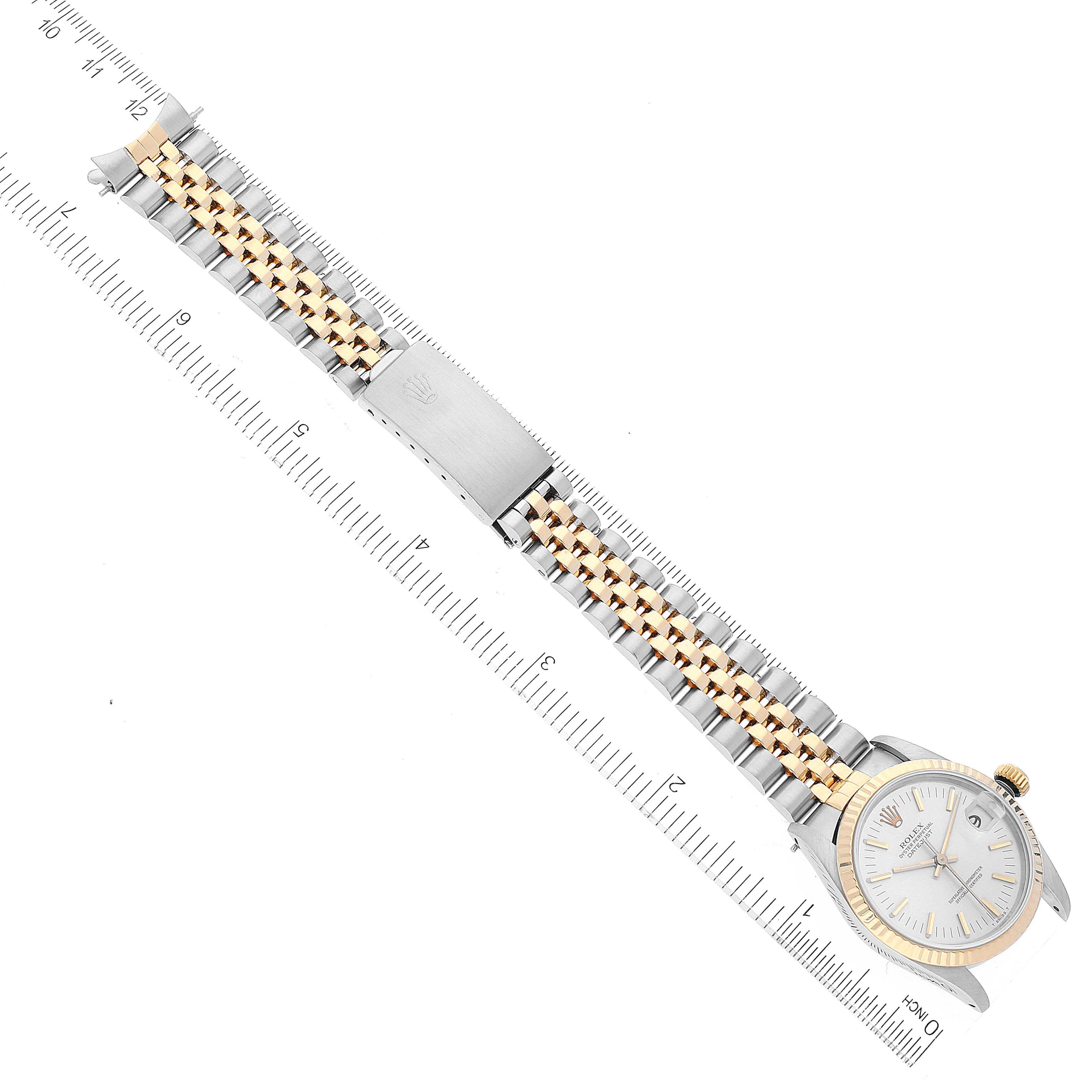 The image shows a flat view of a Mid-Size Rolex watch displaying its face, bezel, and full two-tone band alongside a ruler for scale.