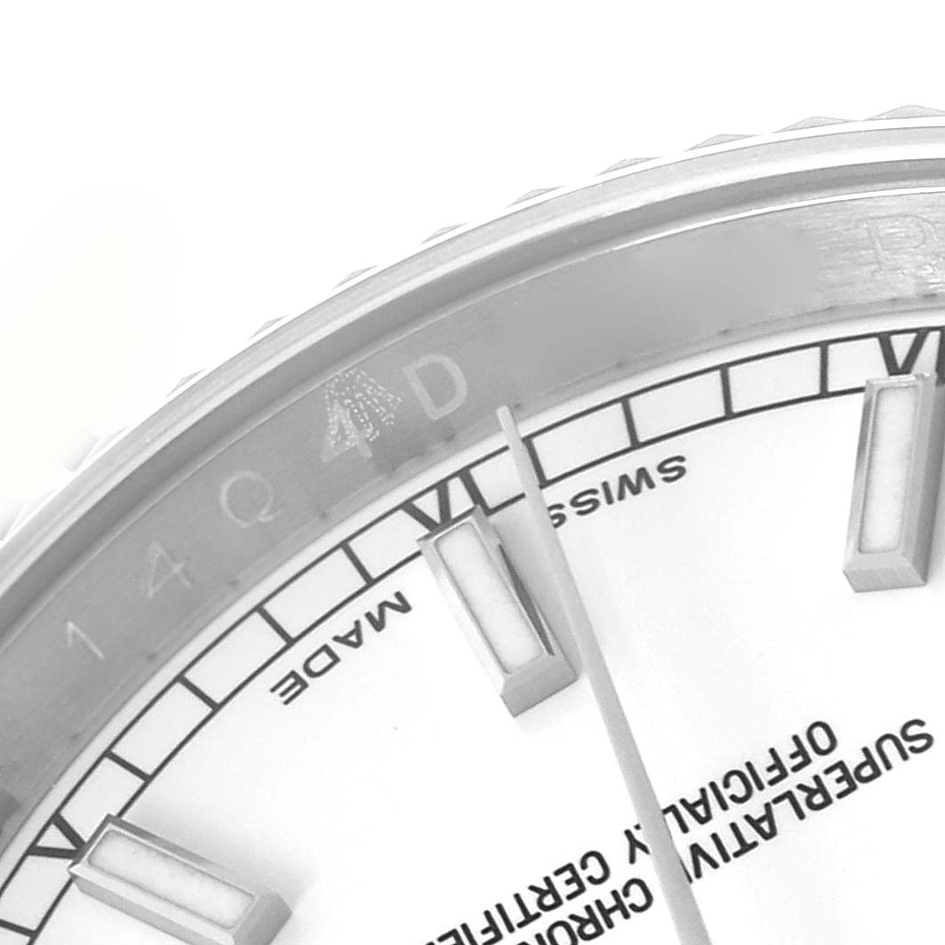 The image shows a partial close-up of a Rolex Datejust 116234 Men
s Stainless Steel White Dial 116234 Men
s Stainless Steel White Dial watch dial focusing on the hour markers and text.