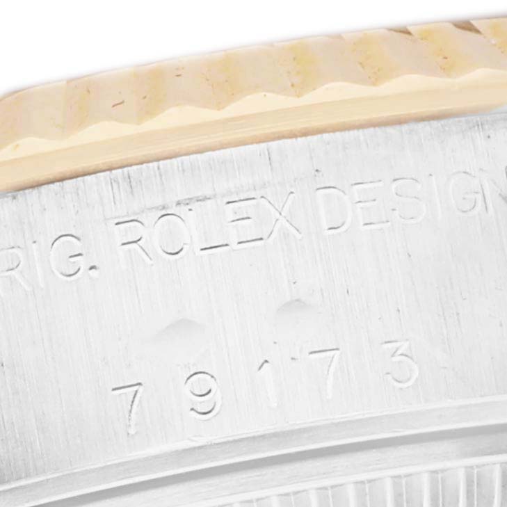 The image shows a close-up of the side of a Rolex Datejust 79173 Women
s Steel and Gold (two tone) White Dial 79173 Women
s Steel and Gold (two tone) White Dial watch, featuring part of the bezel and engraved model details.