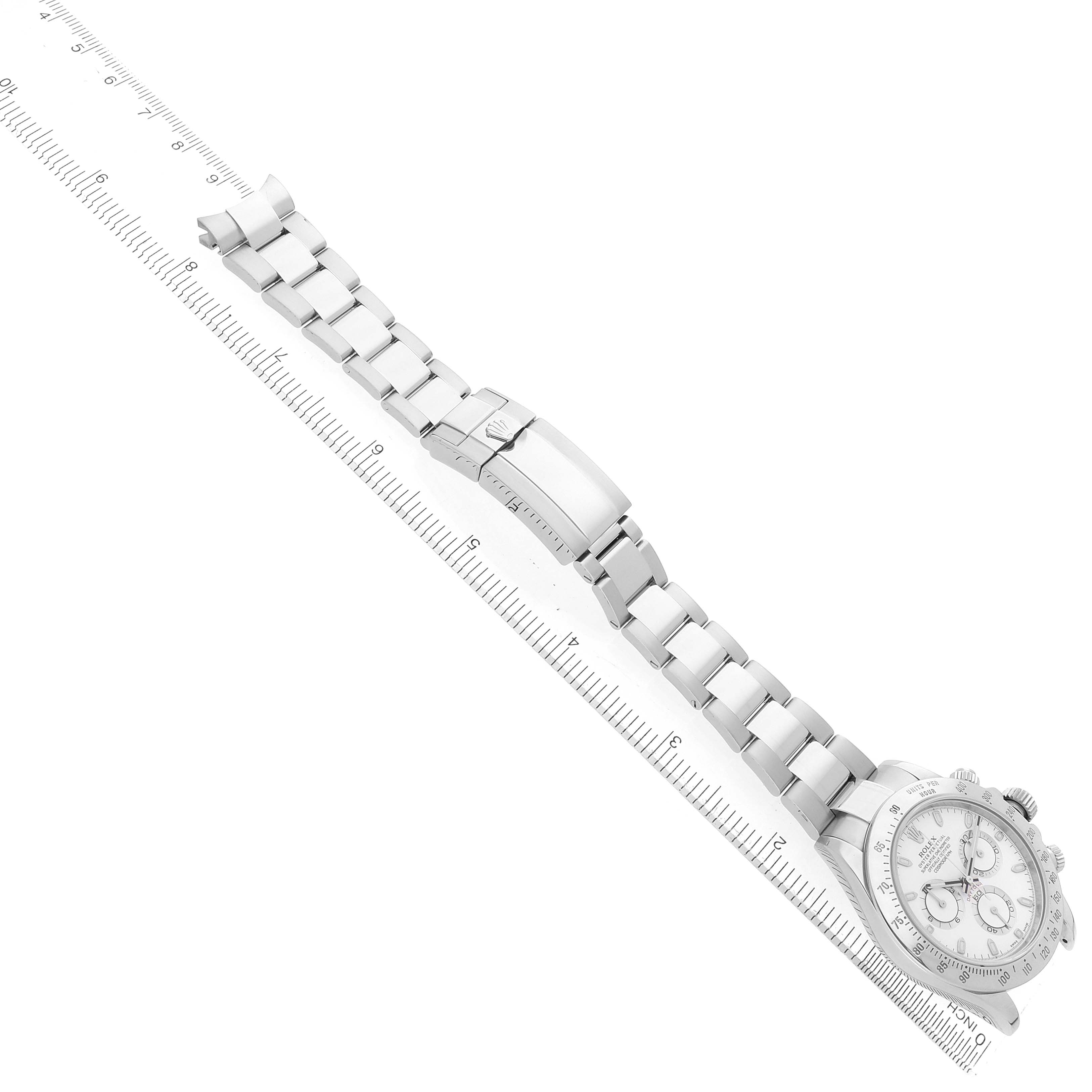 The Rolex Daytona 116520 Men's Stainless Steel White Dial watch is shown from a top-down angle, displaying the full bracelet and clasp alongside a ruler for scale.
