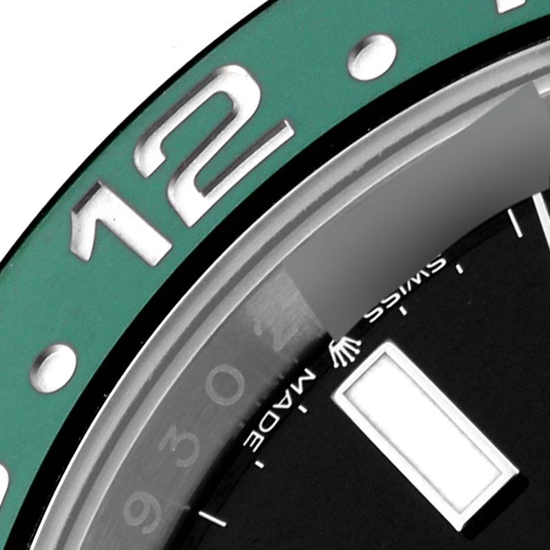 This close-up image shows parts of the bezel and dial of a Rolex GMT-Master 126720VTNR Men's Stainless Steel Black Dial 126720VTNR Men's Stainless Steel Black Dial watch, focusing on the 12-hour marker and surrounding details.