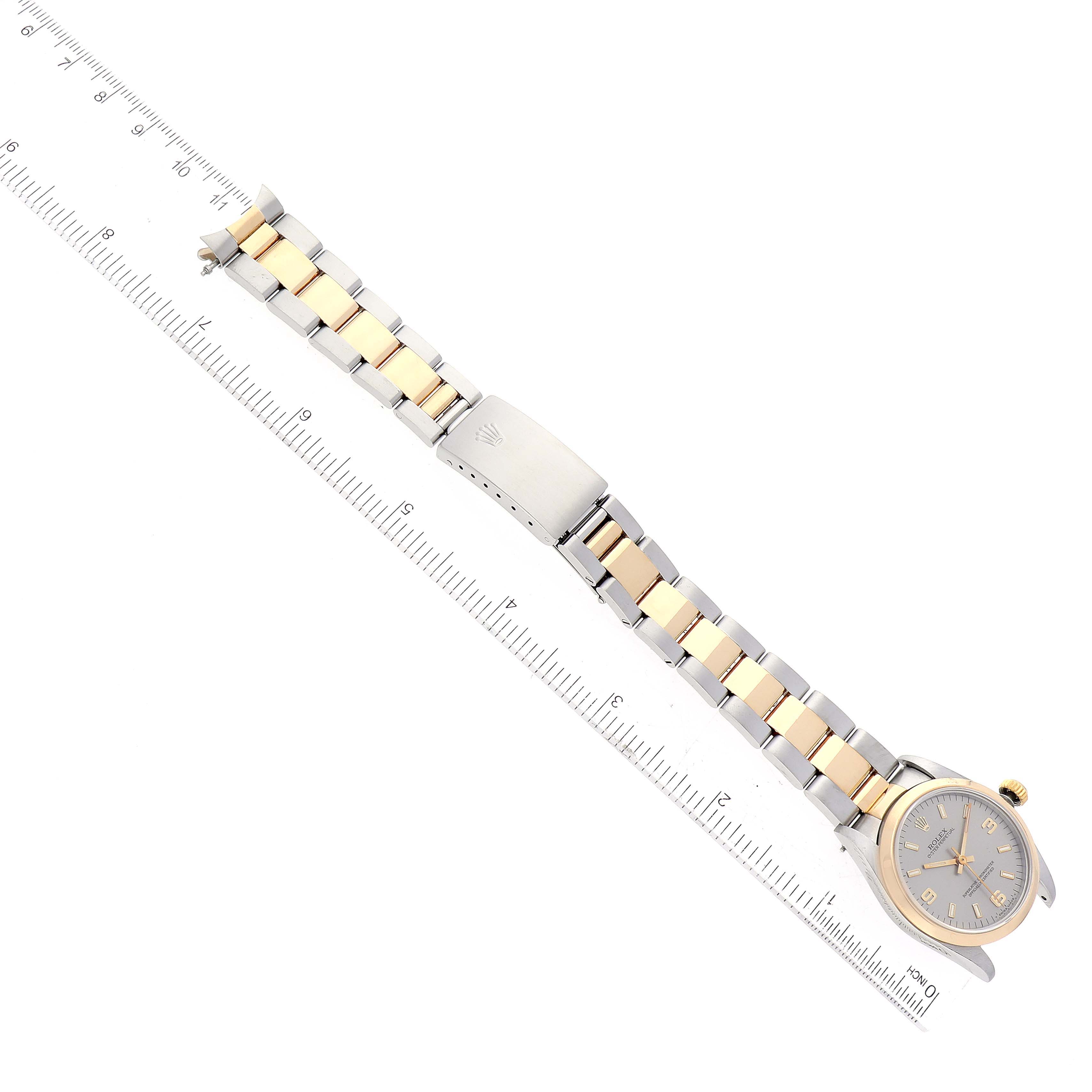 The image shows a top-down view of a Rolex Mid-Size 67483 Women's Steel and Gold (two tone) Silver Dial 67483 Women's Steel and Gold (two tone) Silver Dial model with its full bracelet extended alongside a ruler for scale.